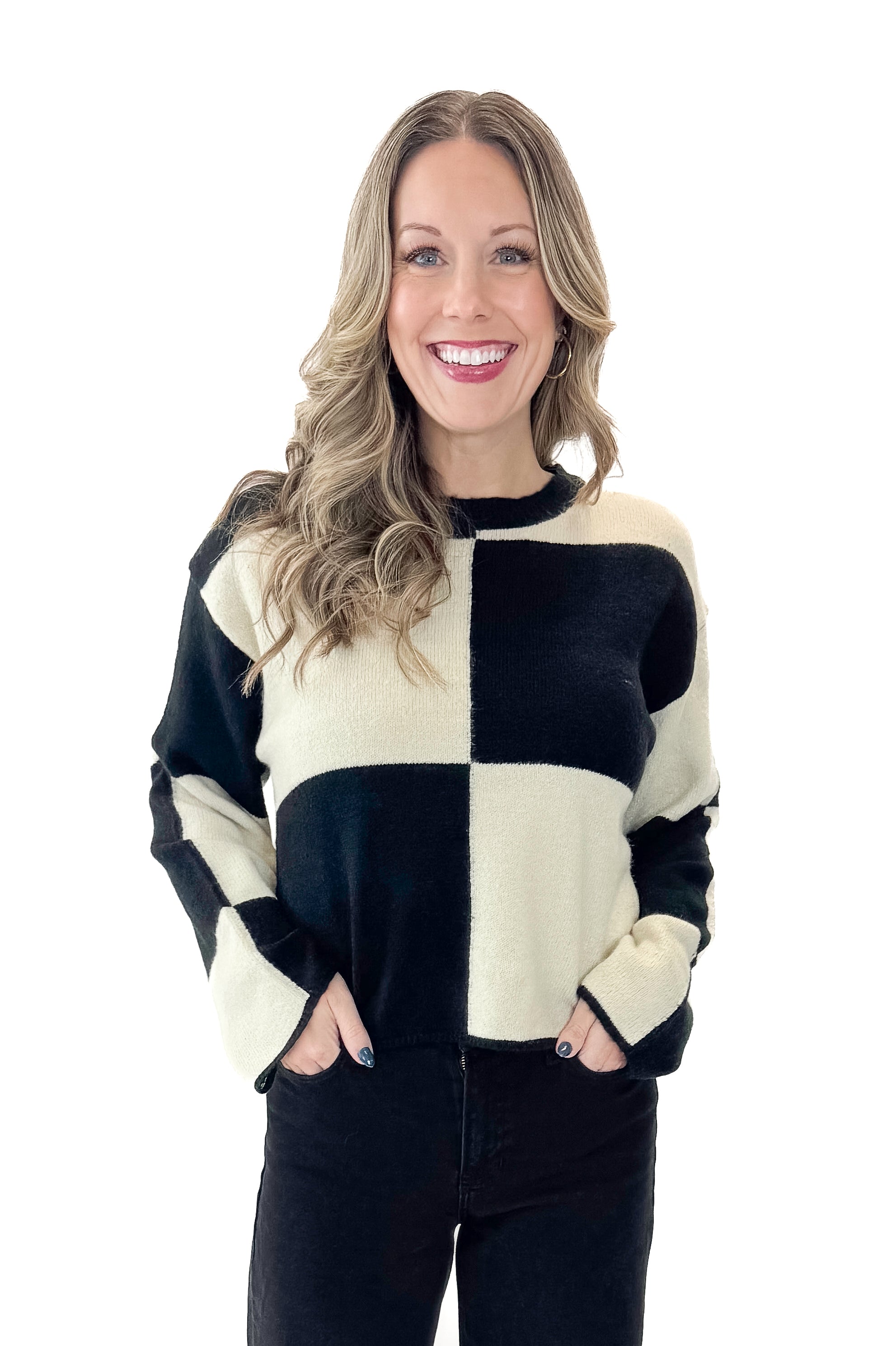 Front view of woman wearing Black & Cream Checkered Sweater with jeans against white studio background.