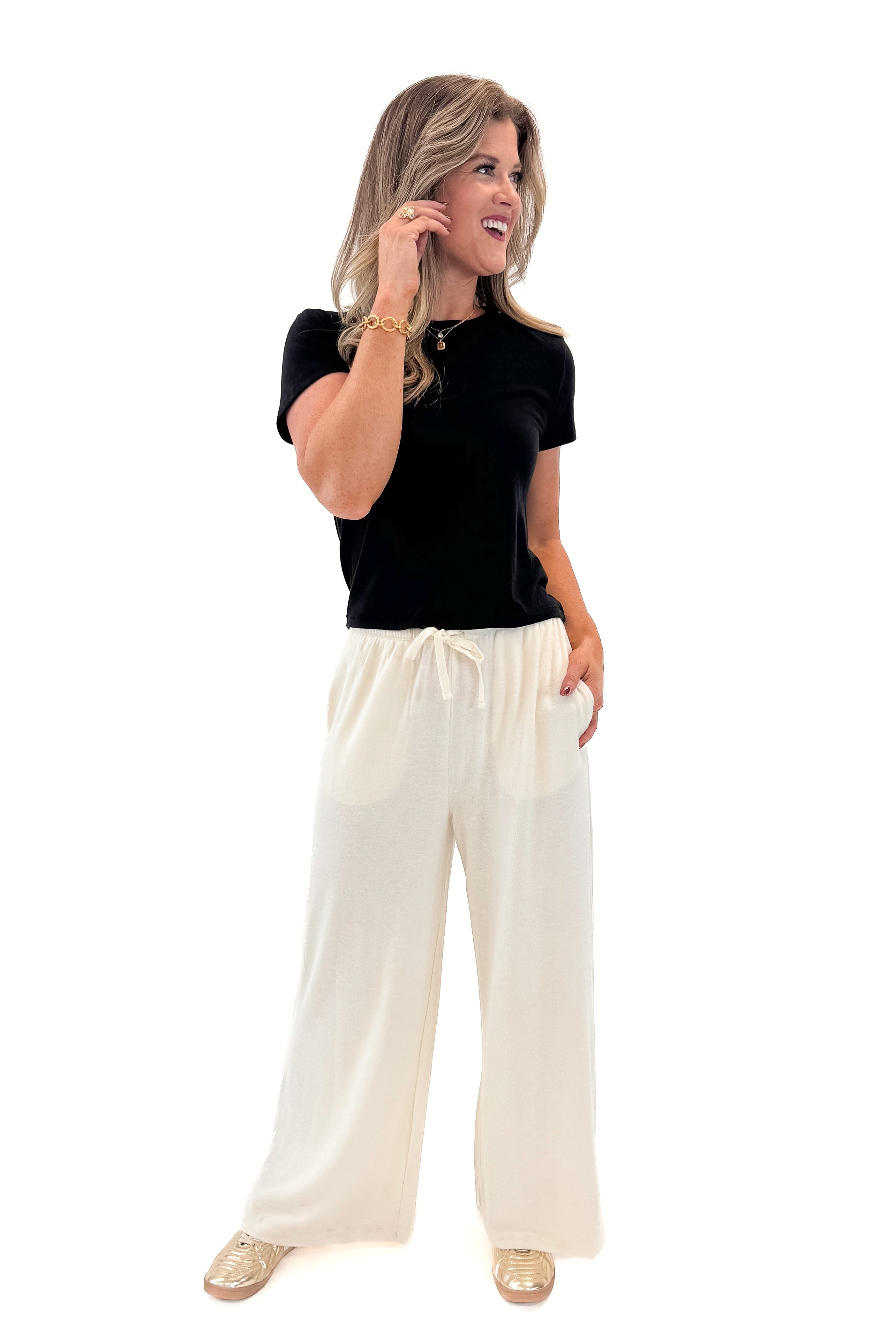 Front view of woman wearing black top with Cream Brushed Wide Leg Sweatpants against white studio background.