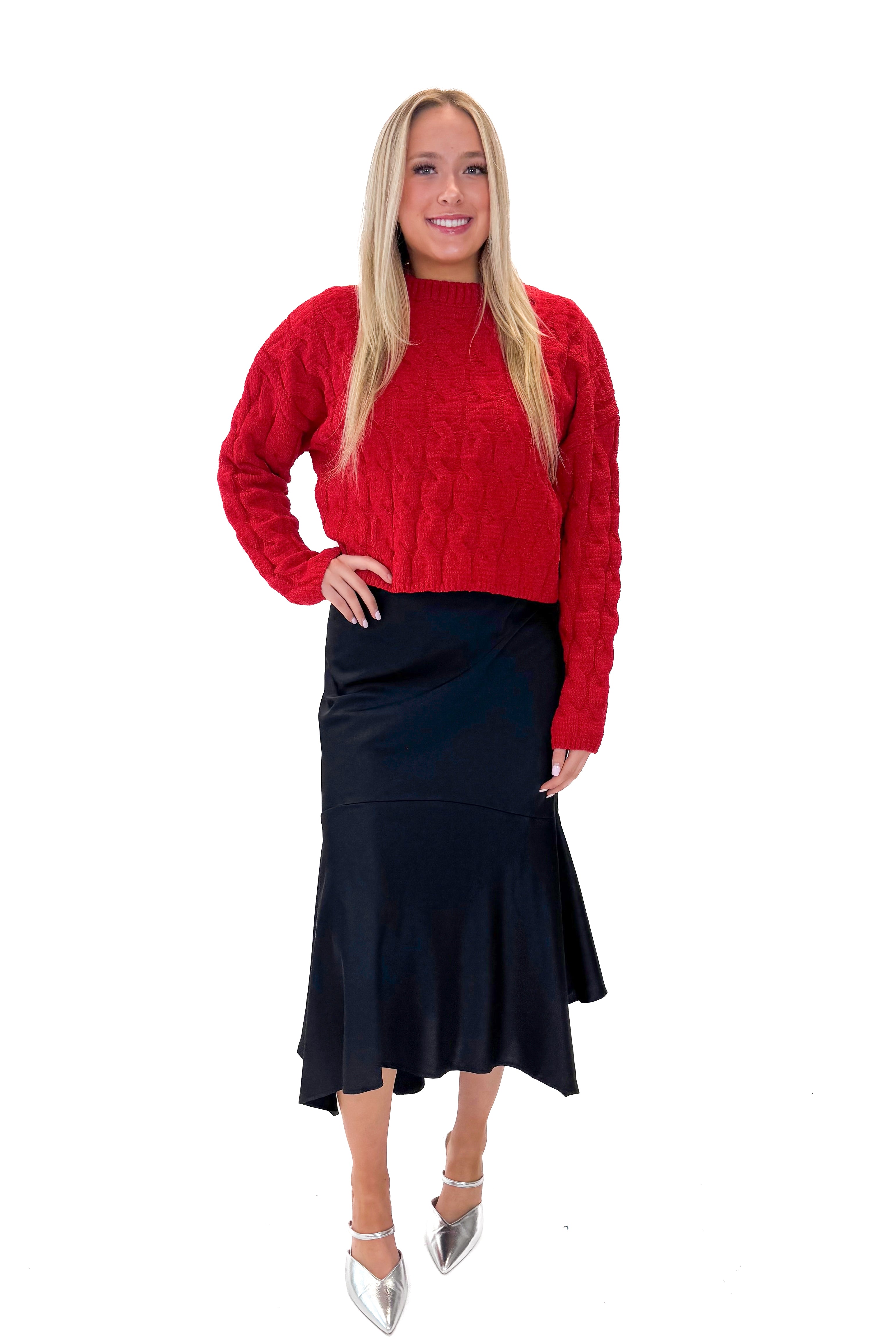 Front view of woman wearing Red Textured Cable Knit Sweater with skirt against white studio background.