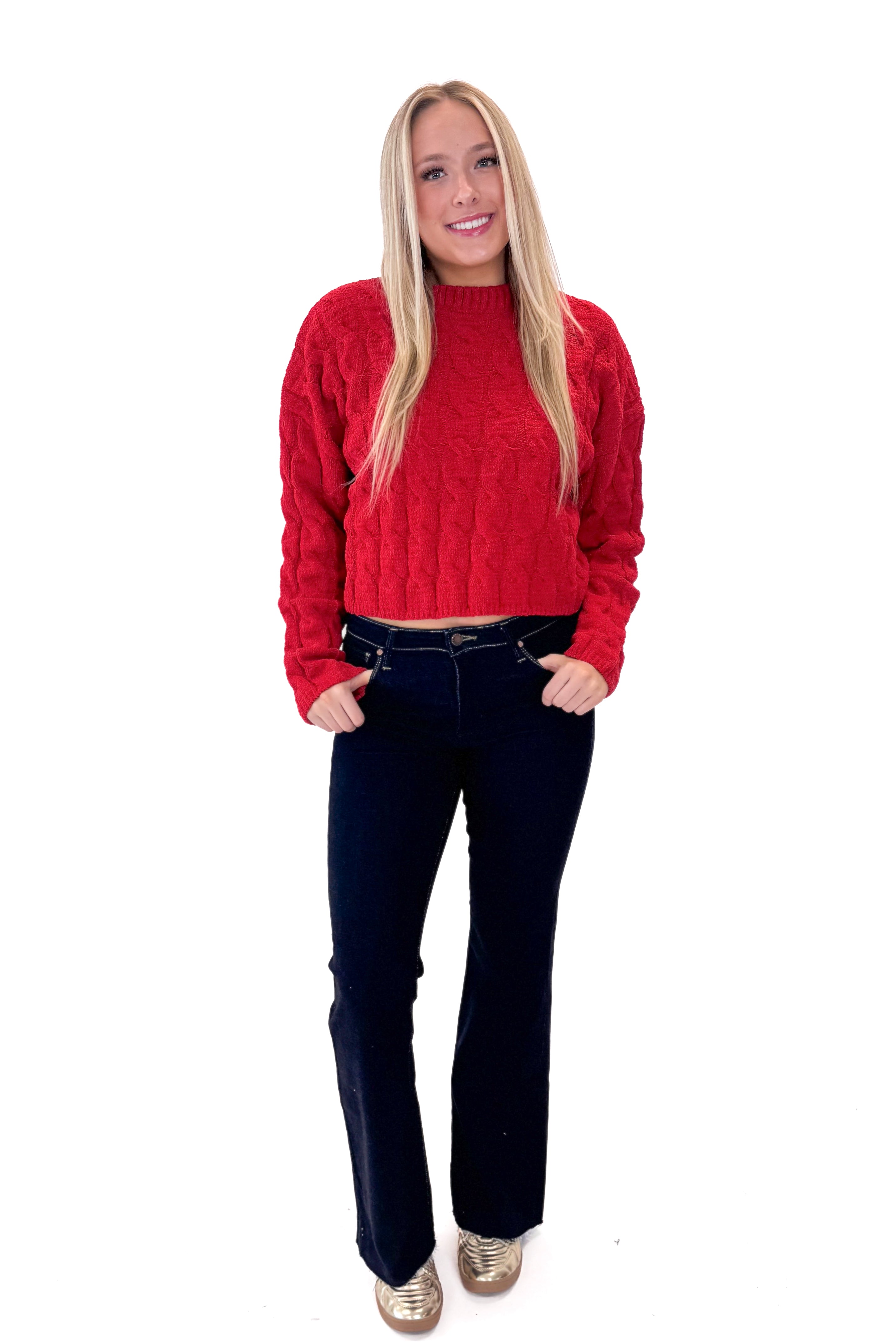 Front view of woman wearing Red Textured Cable Knit Sweater with jeans against white studio background.