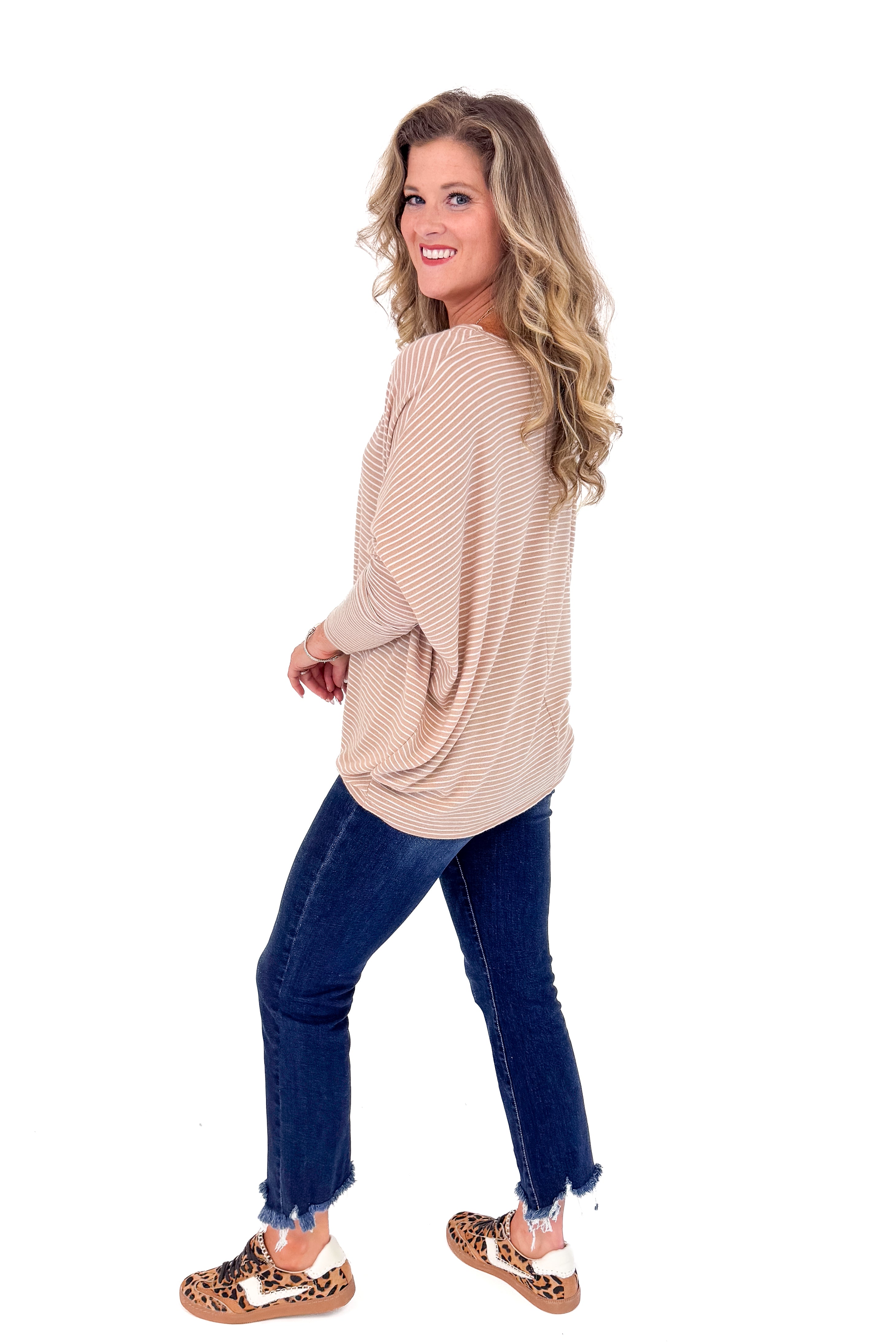 Woman wearing a beige sweater and blue jeans on a white background