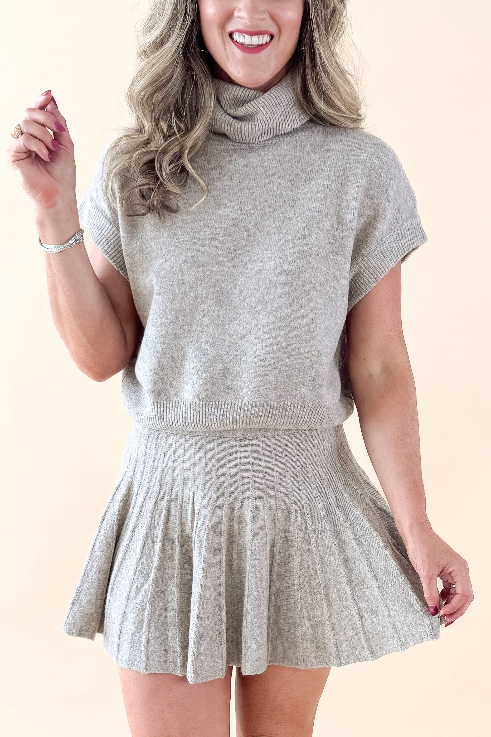 Front view of woman wearing Taupe Mock Neck Short Sleeve Sweater with matching skirt against tan studio background.