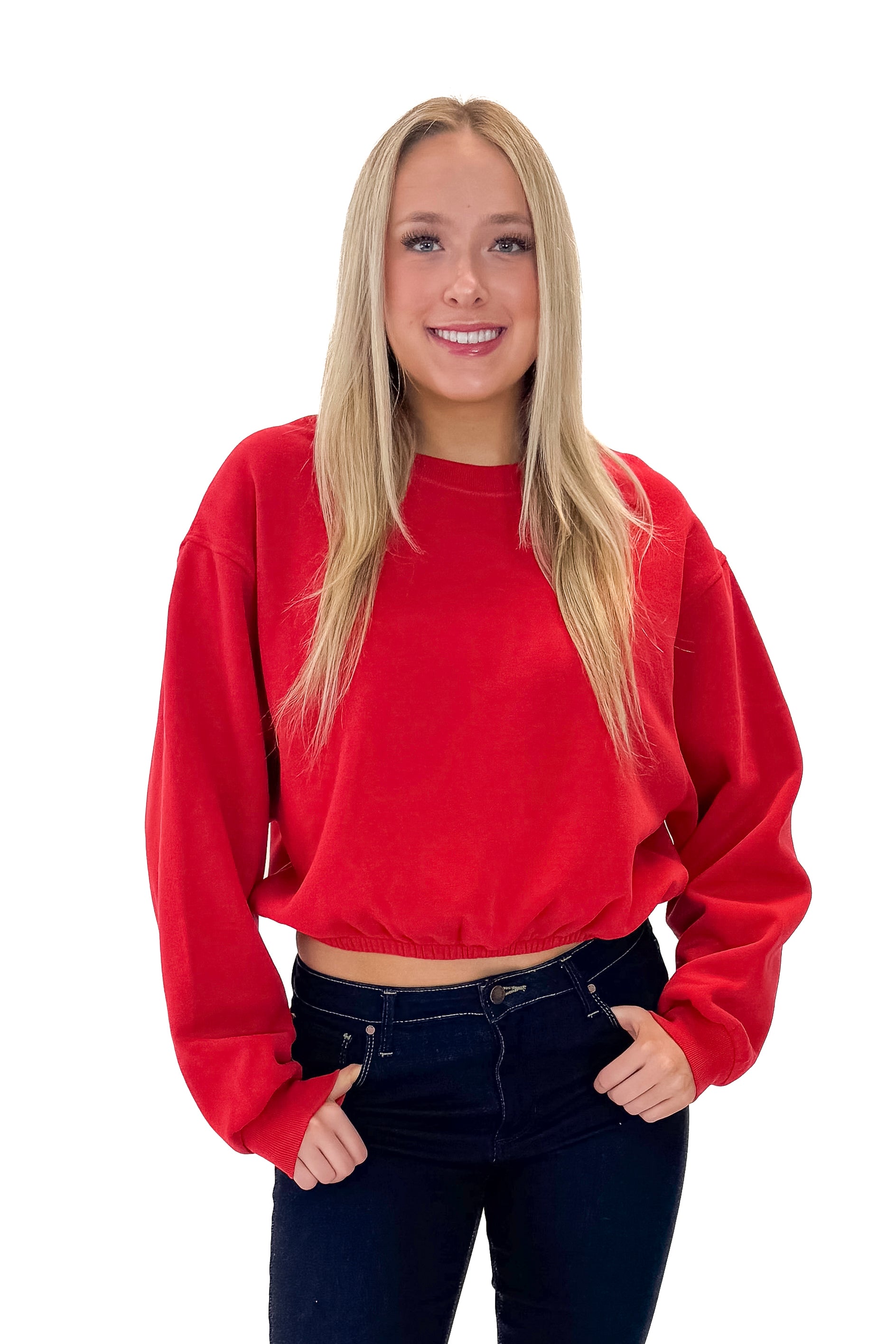 Front view of woman wearing Red Elastic Hem Sweatshirt with jeans against white studio background.