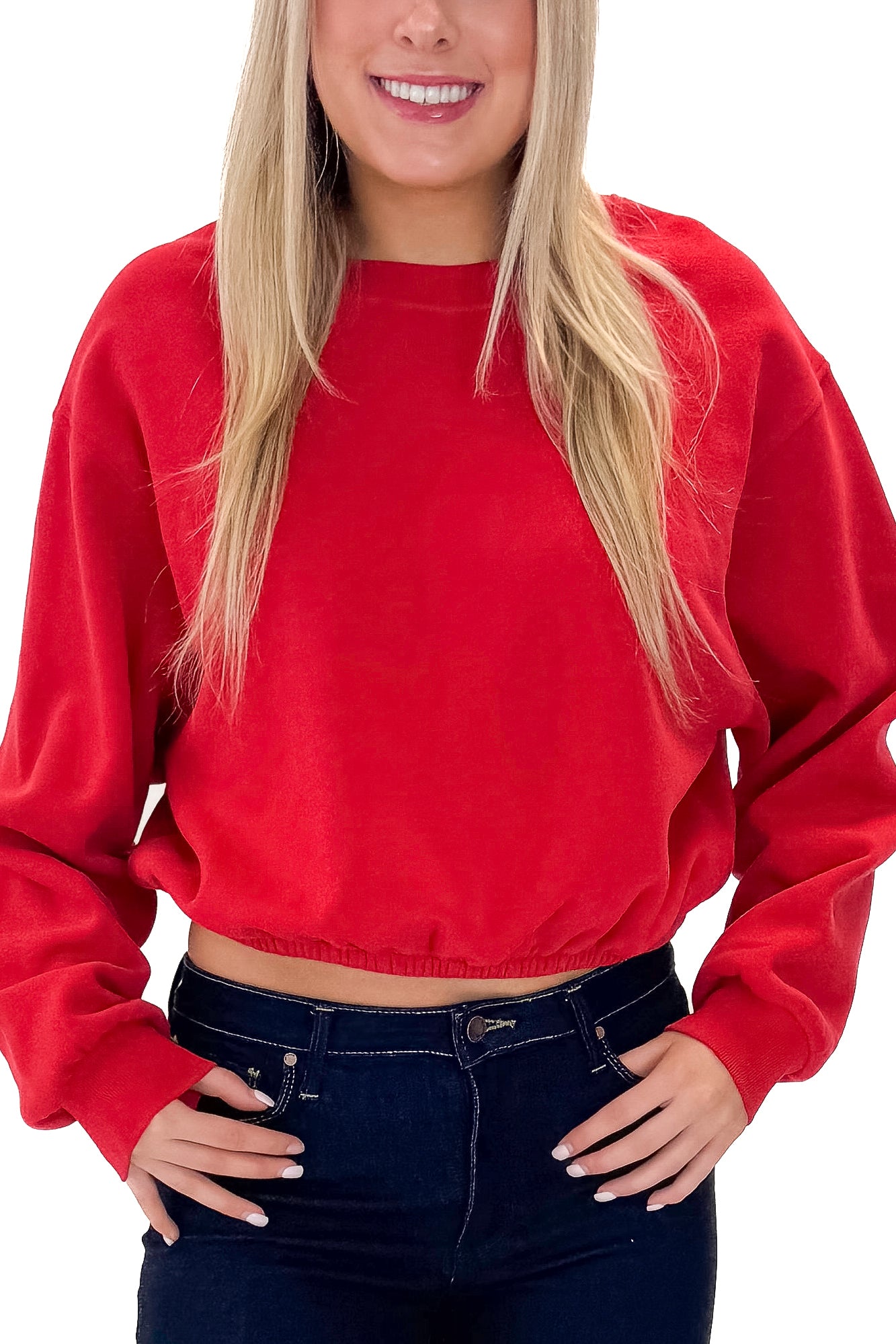 Front detail view of woman wearing Red Elastic Hem Sweatshirt with jeans against white studio background.