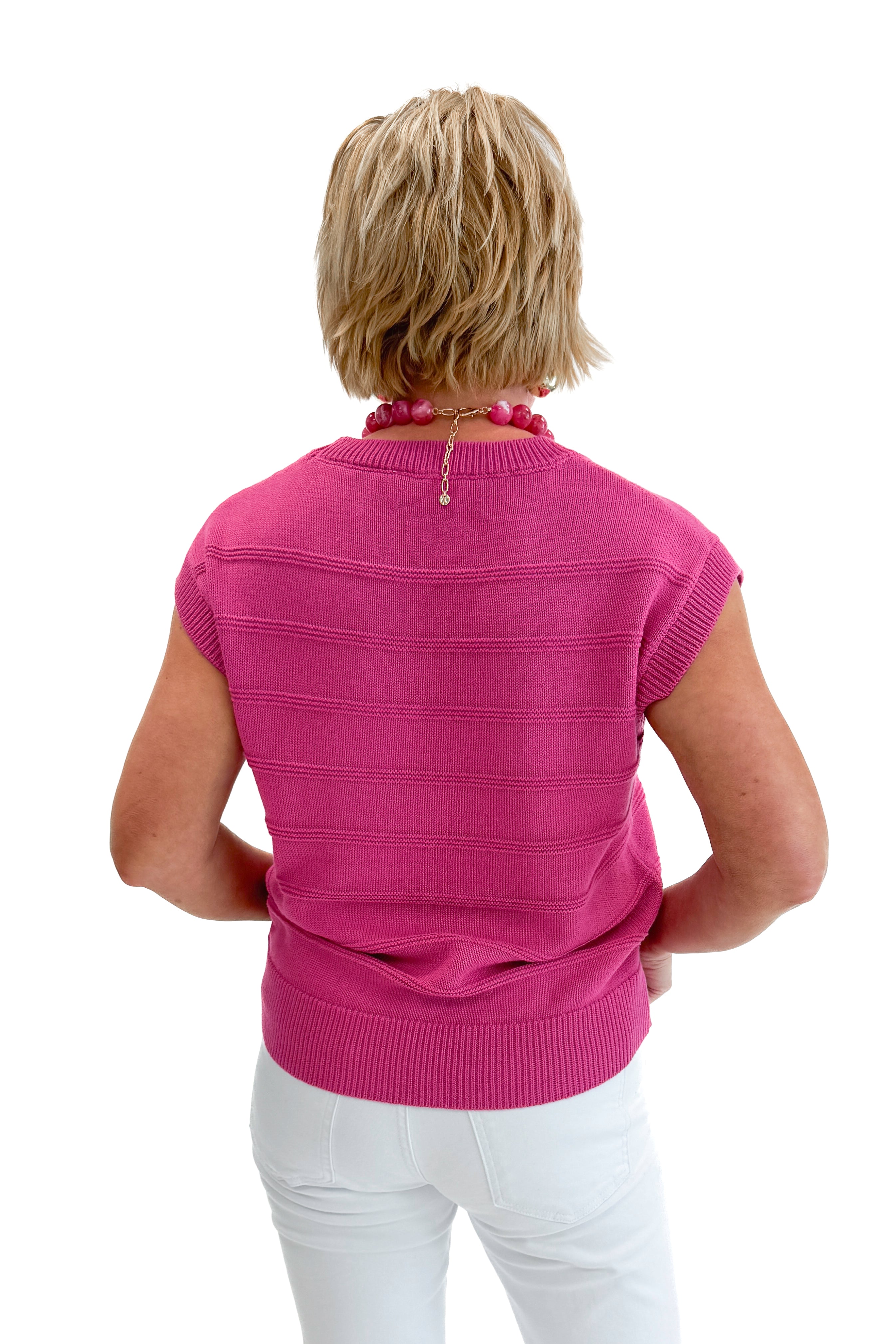 Back view of woman wearing Fuchsia Textured Detail Sleeveless Sweater with jeans against white studio background.