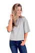 Woman wearing a gray oversized t-shirt and blue jeans on a white background