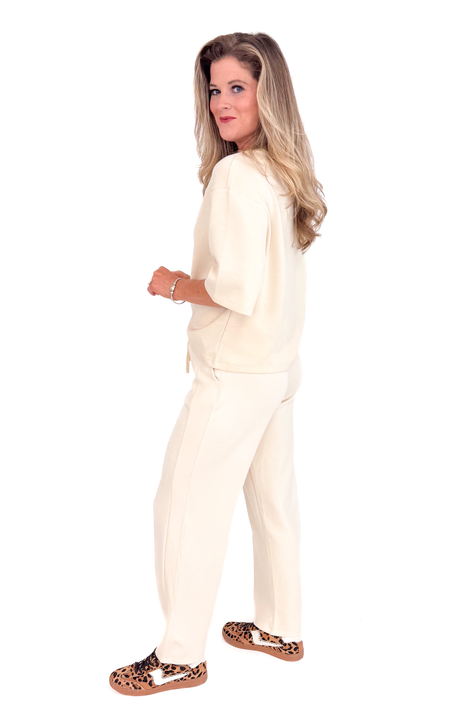 Woman wearing a white suit with leopard print shoes on a white background