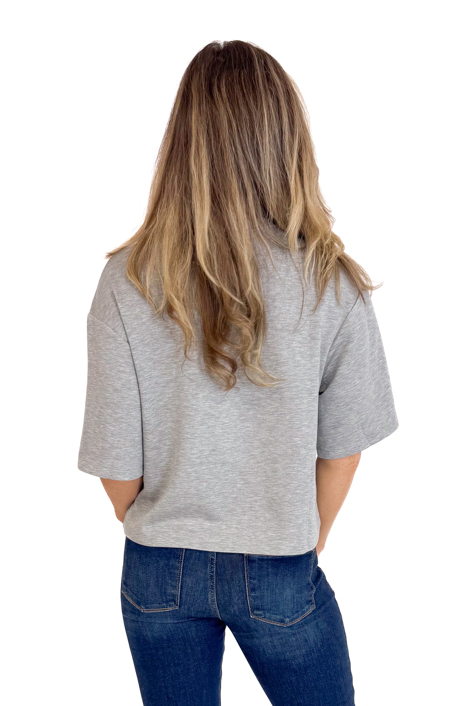 Person wearing a gray t-shirt and blue jeans on a white background