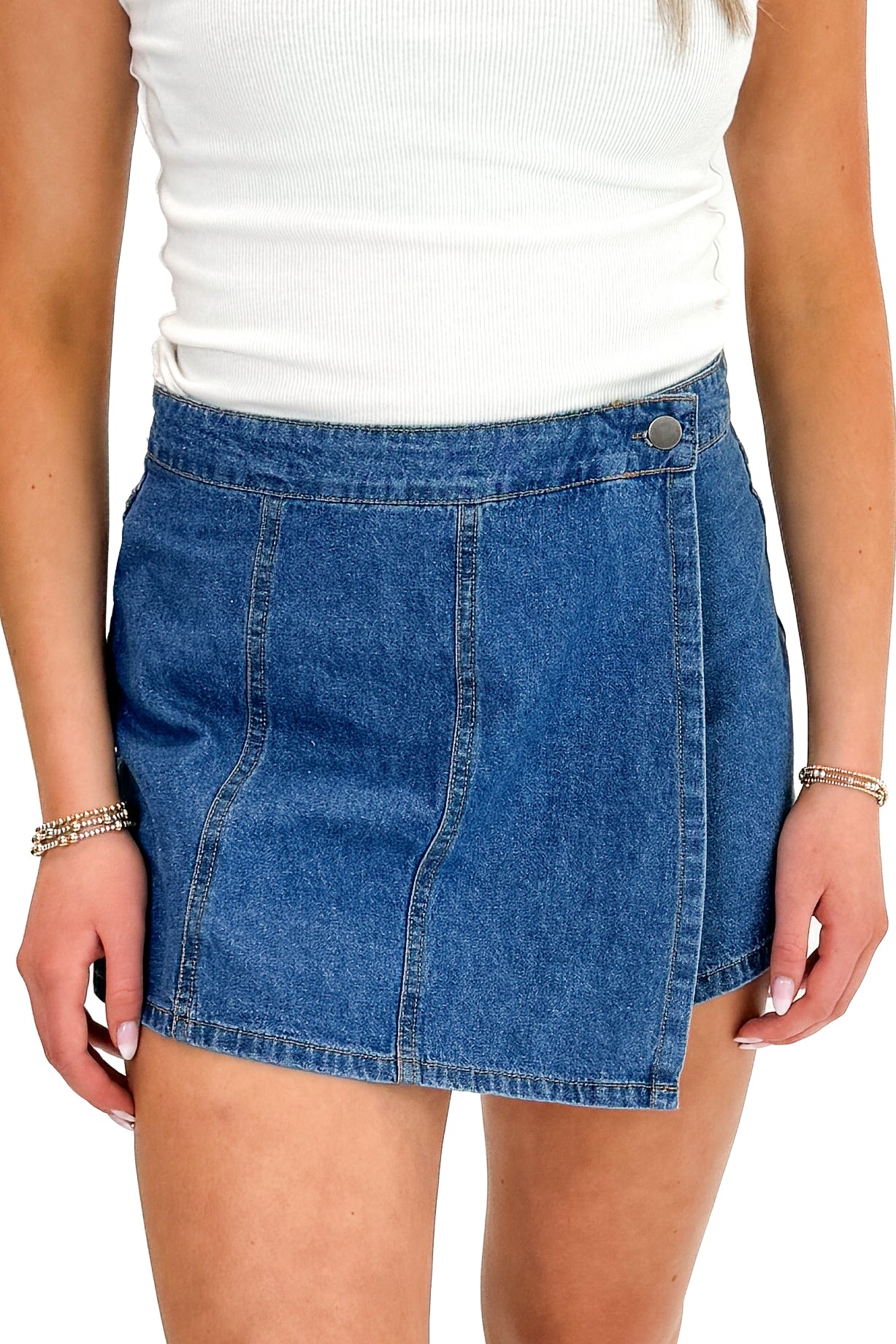 Front detail view of woman wearing white top with Medium Wash Denim Wrap Skort against white studio background.