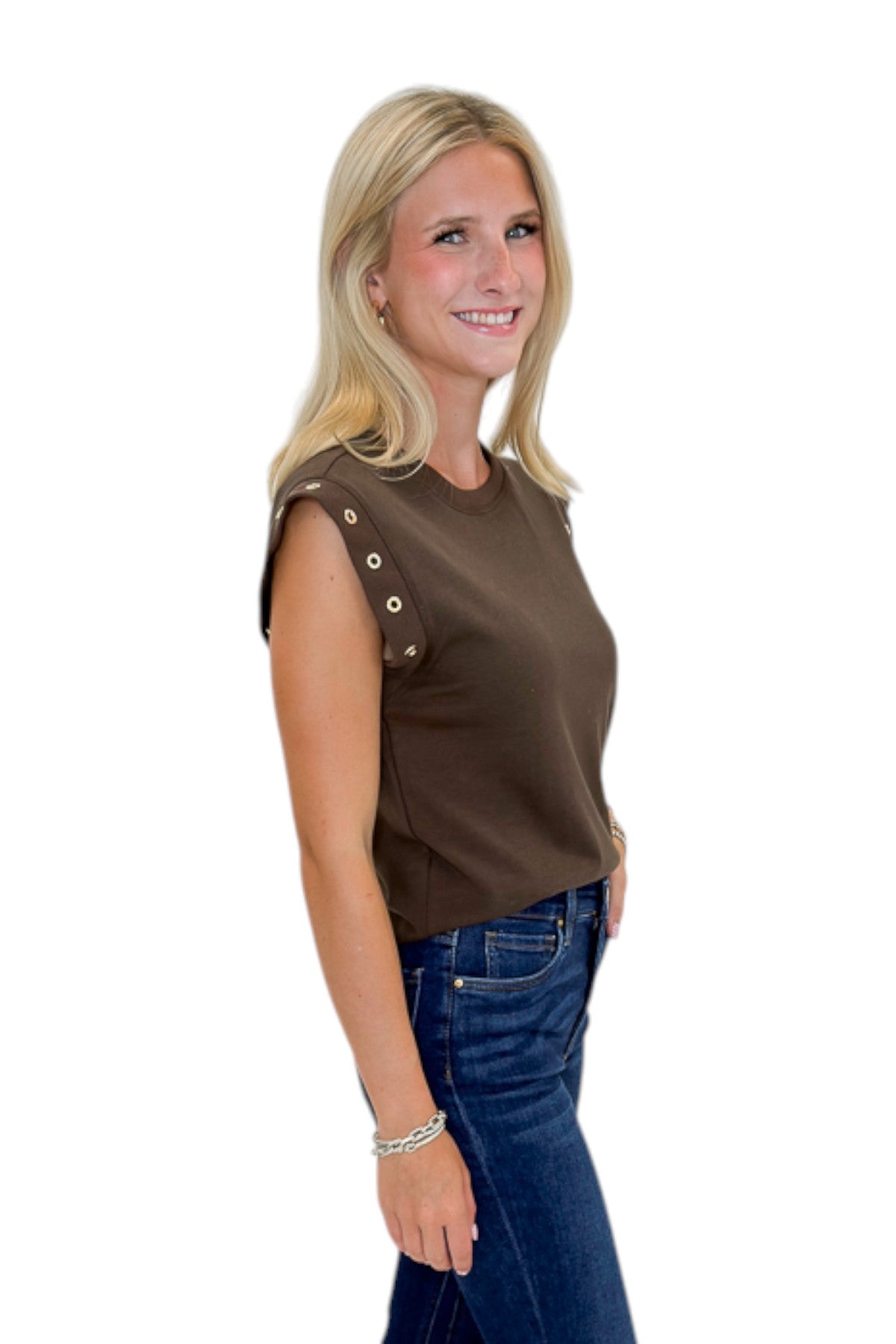 Side view of woman wearing Swagger Boutique’s Dark Chocolate Camino Grommet Top by Z Supply with jeans against white studio background.