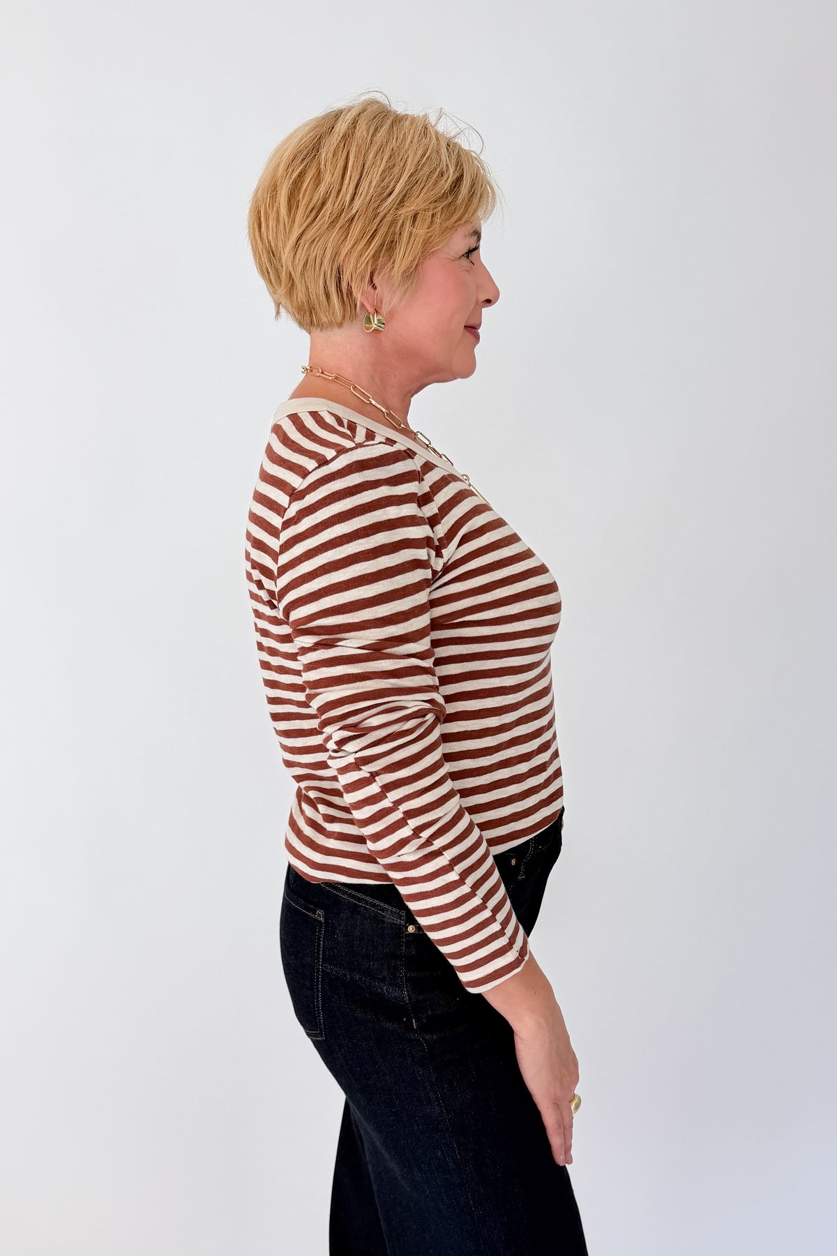 Side view of woman wearing Swagger Boutique’s Dark Rosewood Junie Long Sleeve Stripe Slub Tee by Z Supply with jeans against white studio background.