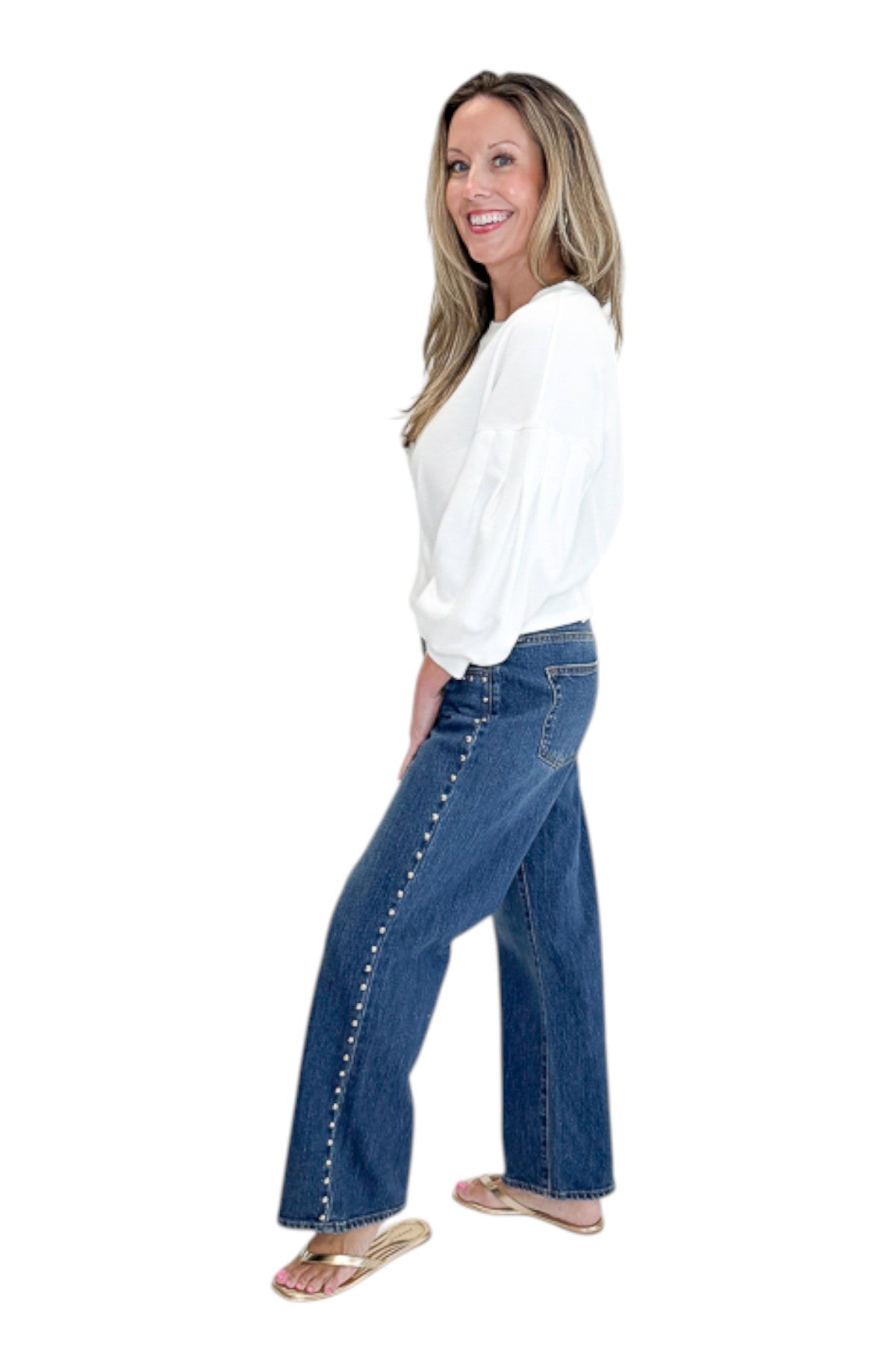 Side view of woman wearing Swagger Boutiqueās sweater with Dark Wash Stud Jeans by Just Black Denim against white studio background.
