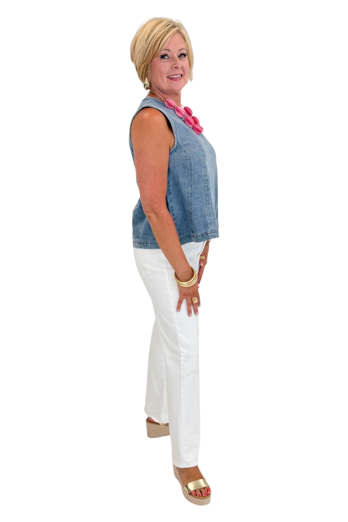 Side view of woman wearing Swagger Boutiqueās Denim Seamed Sleeveless Top with jeans against white studio background.