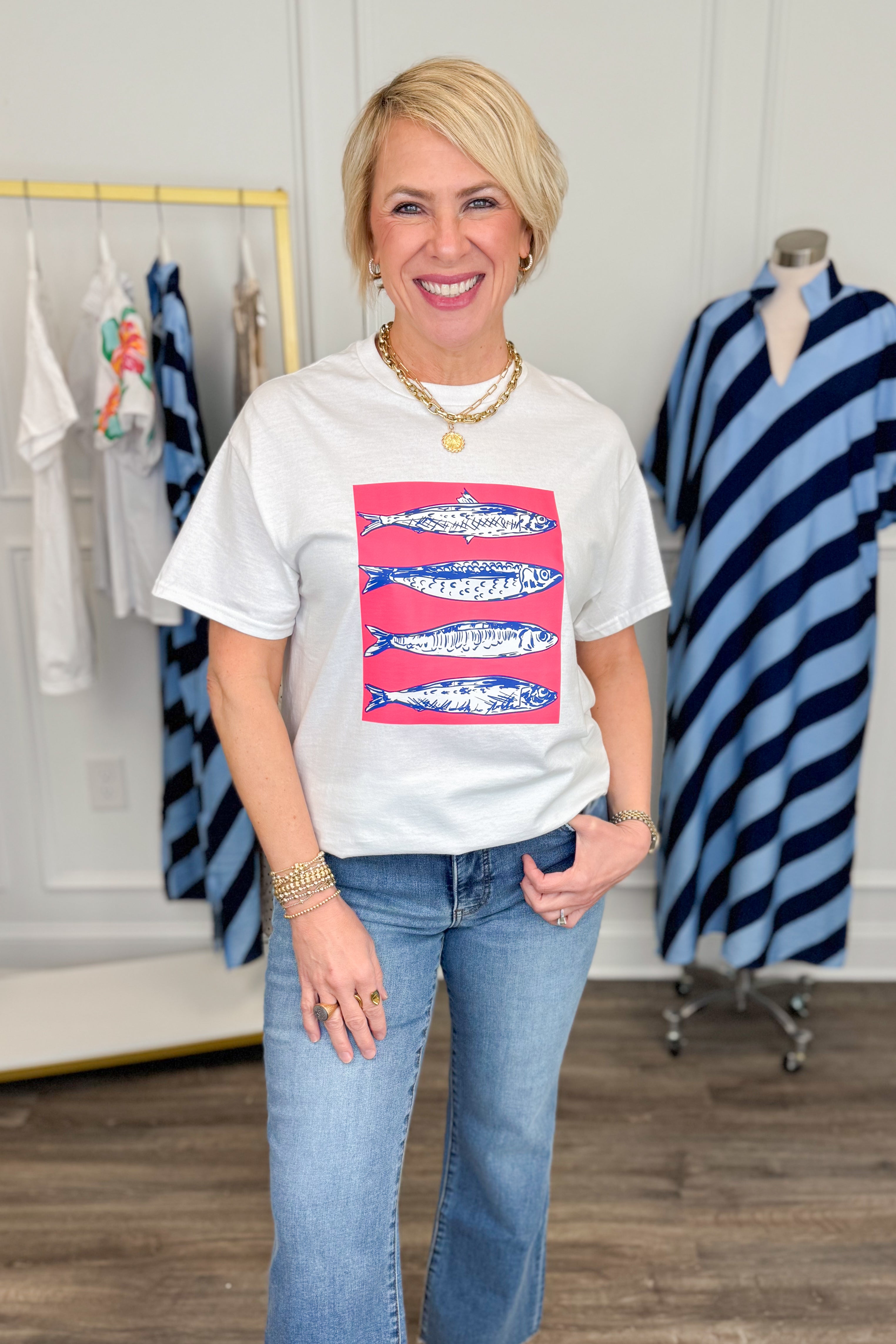 Woman wearing a white t-shirt with a colorful graphic design, standing in a clothing store.