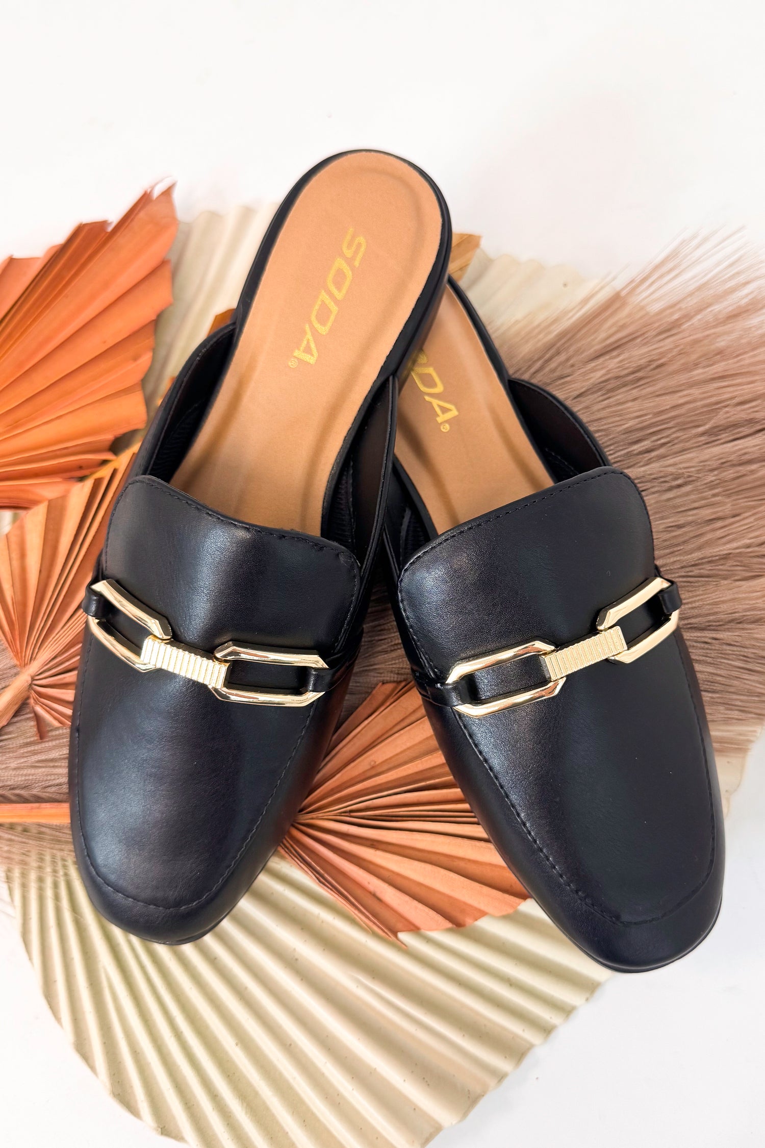 Black loafers with gold buckles on a decorative background