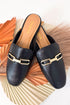 Black loafers with gold buckles on a decorative background