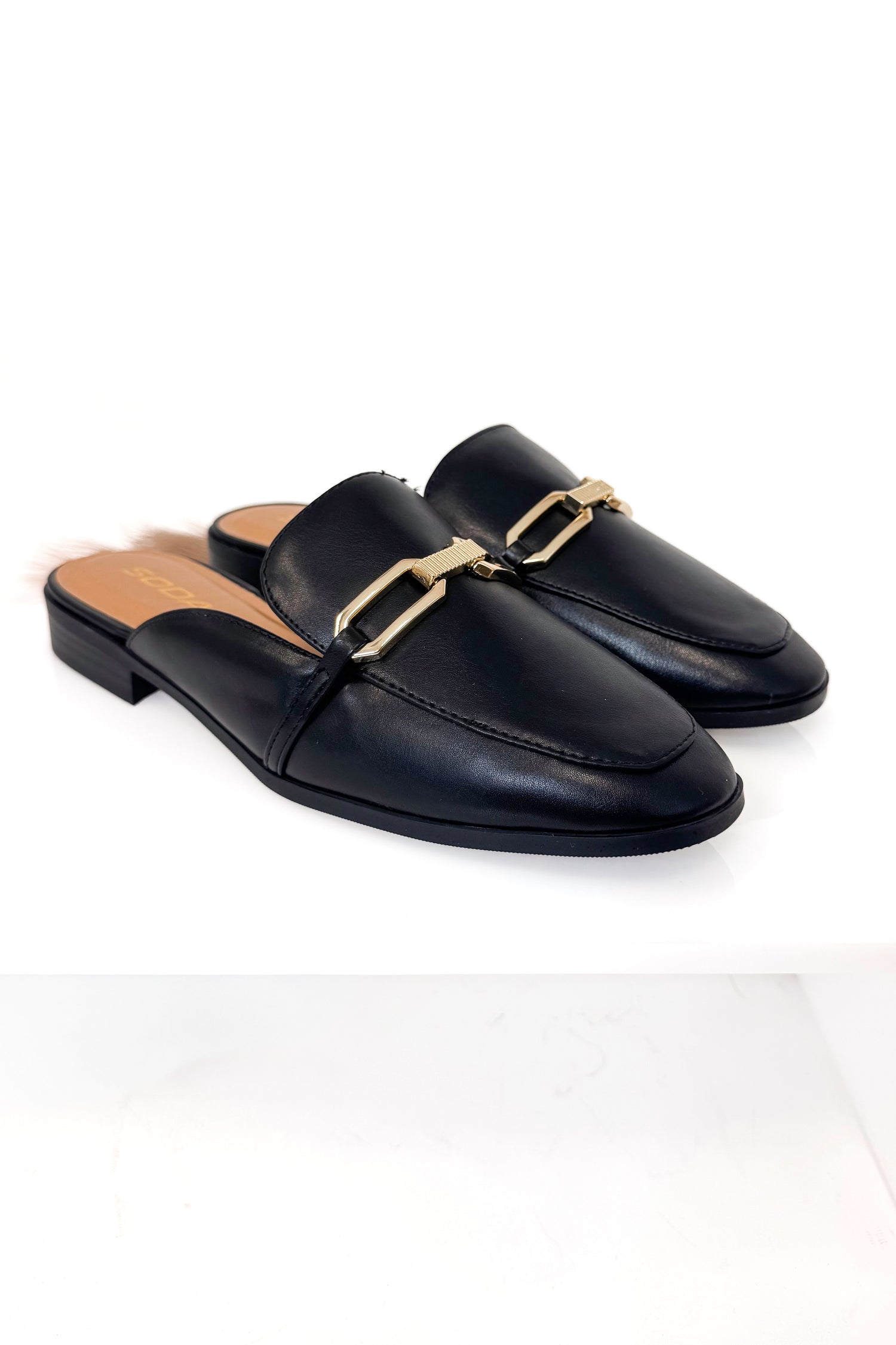 Black loafers with gold accents on a white background