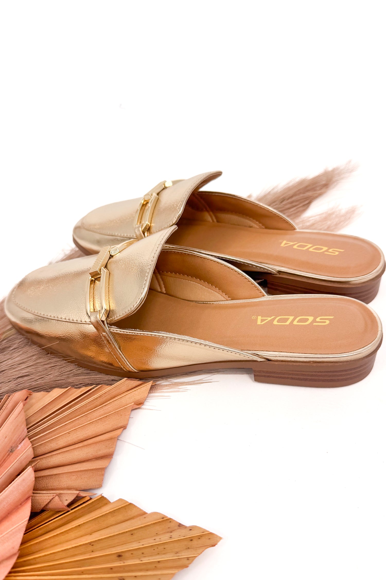 Gold sandals with a brand logo on a white background