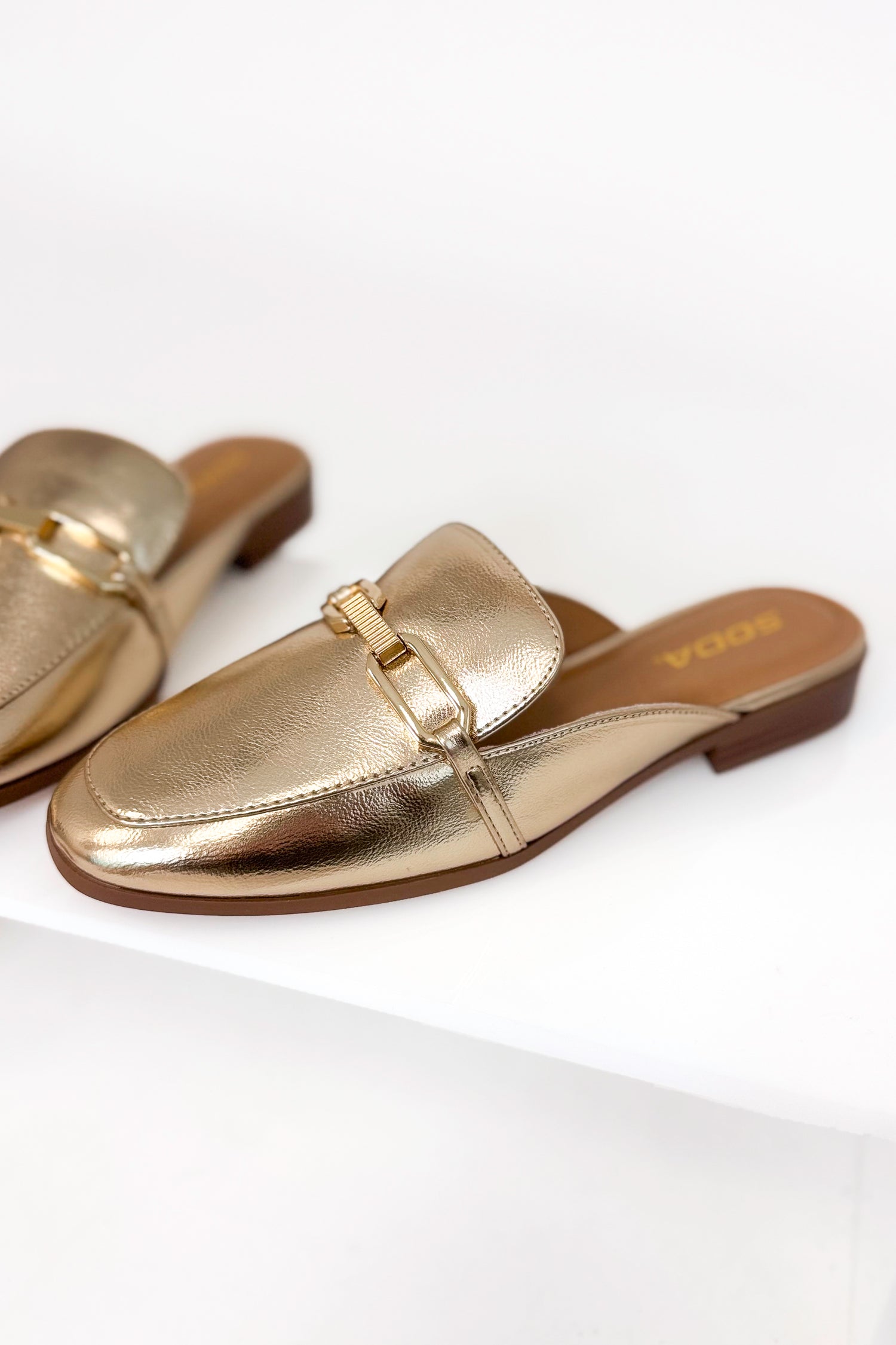 Gold metallic loafers on a white background
