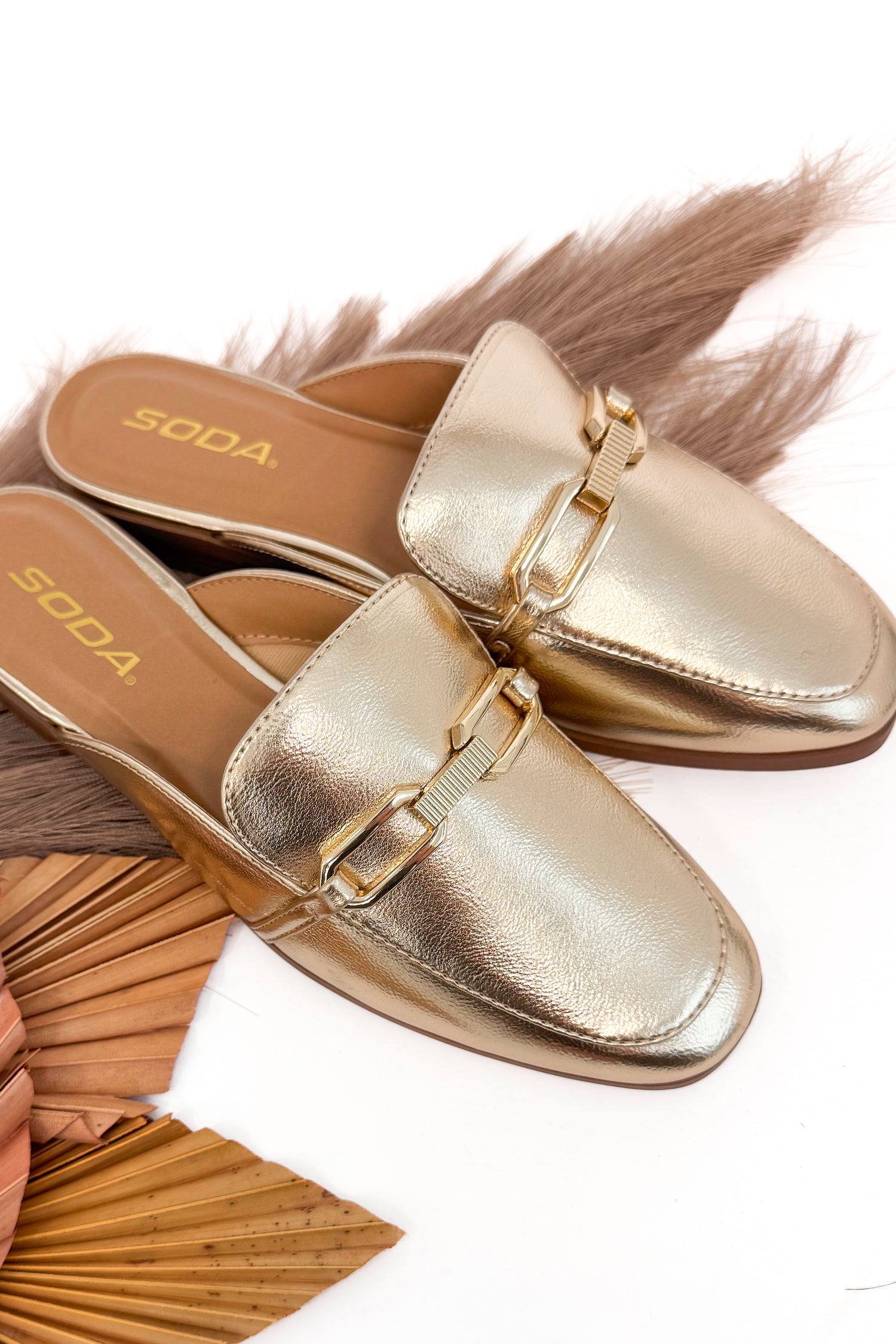 Gold metallic loafers on a white background