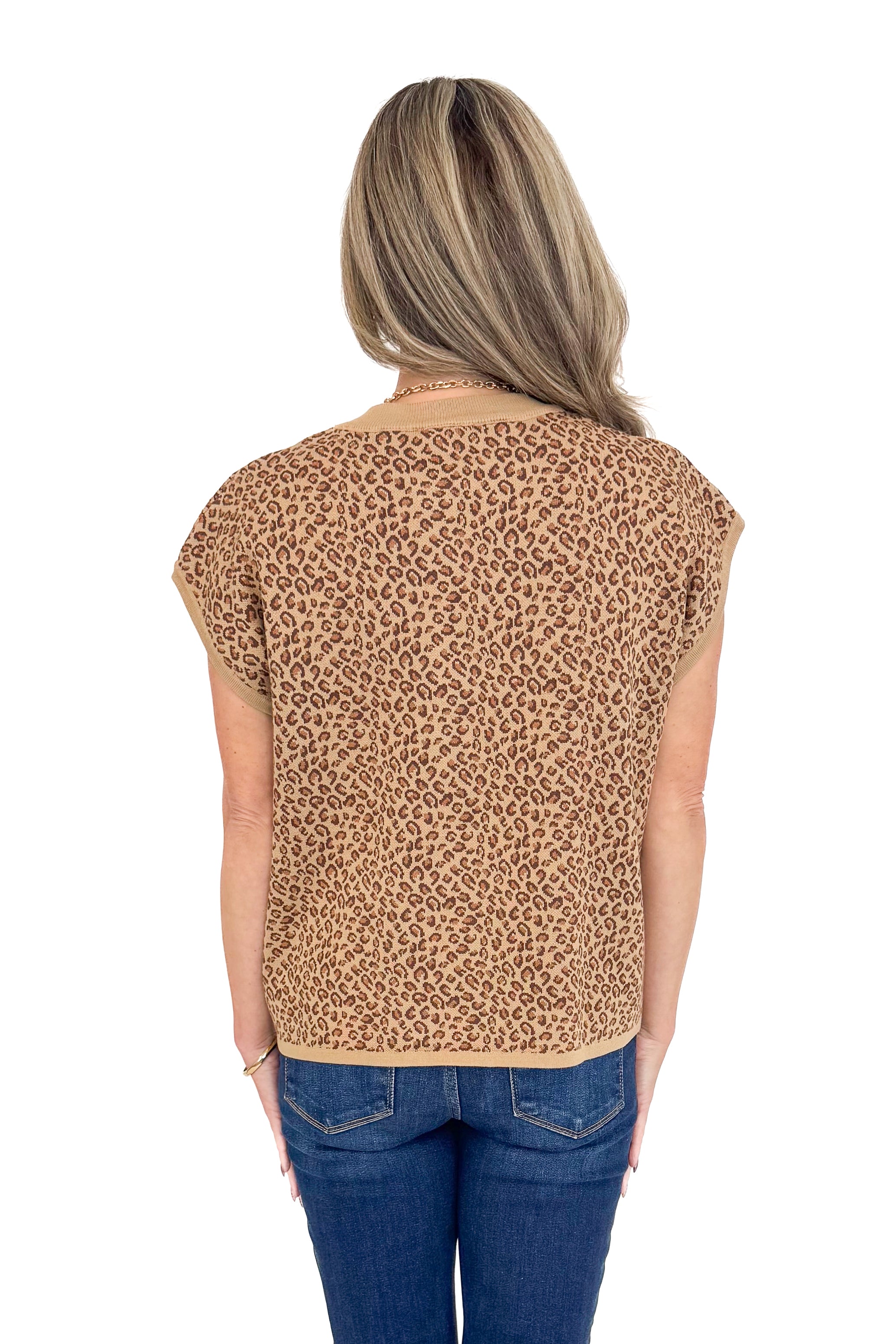 Back view of woman wearing leopard top with jeans against white studio background.