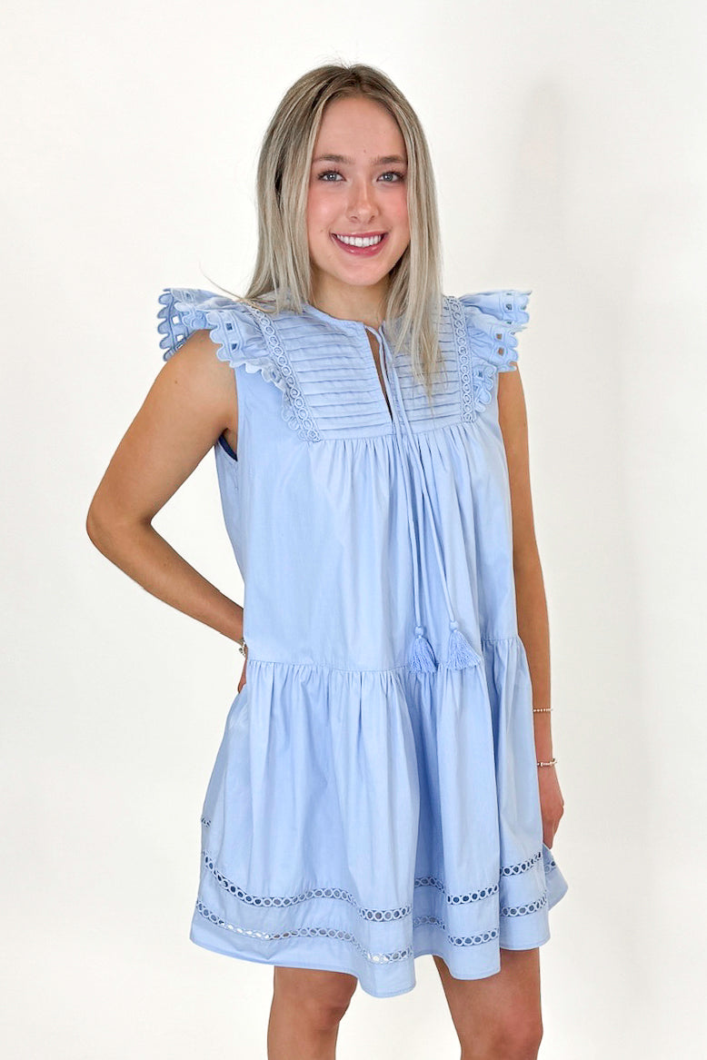 Side view of woman wearing Light Blue Eyelet Detail Dress with sandals against white studio background.