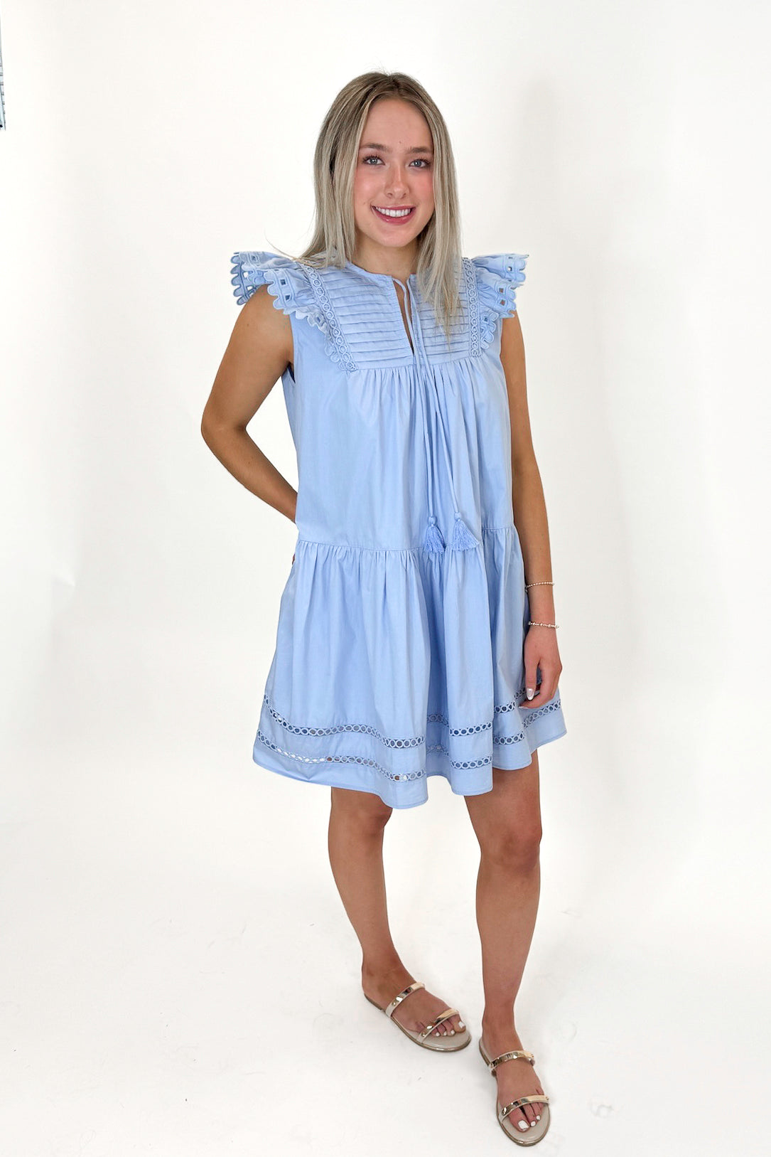 Side view of woman wearing Light Blue Eyelet Detail Dress with sandals against white studio background.