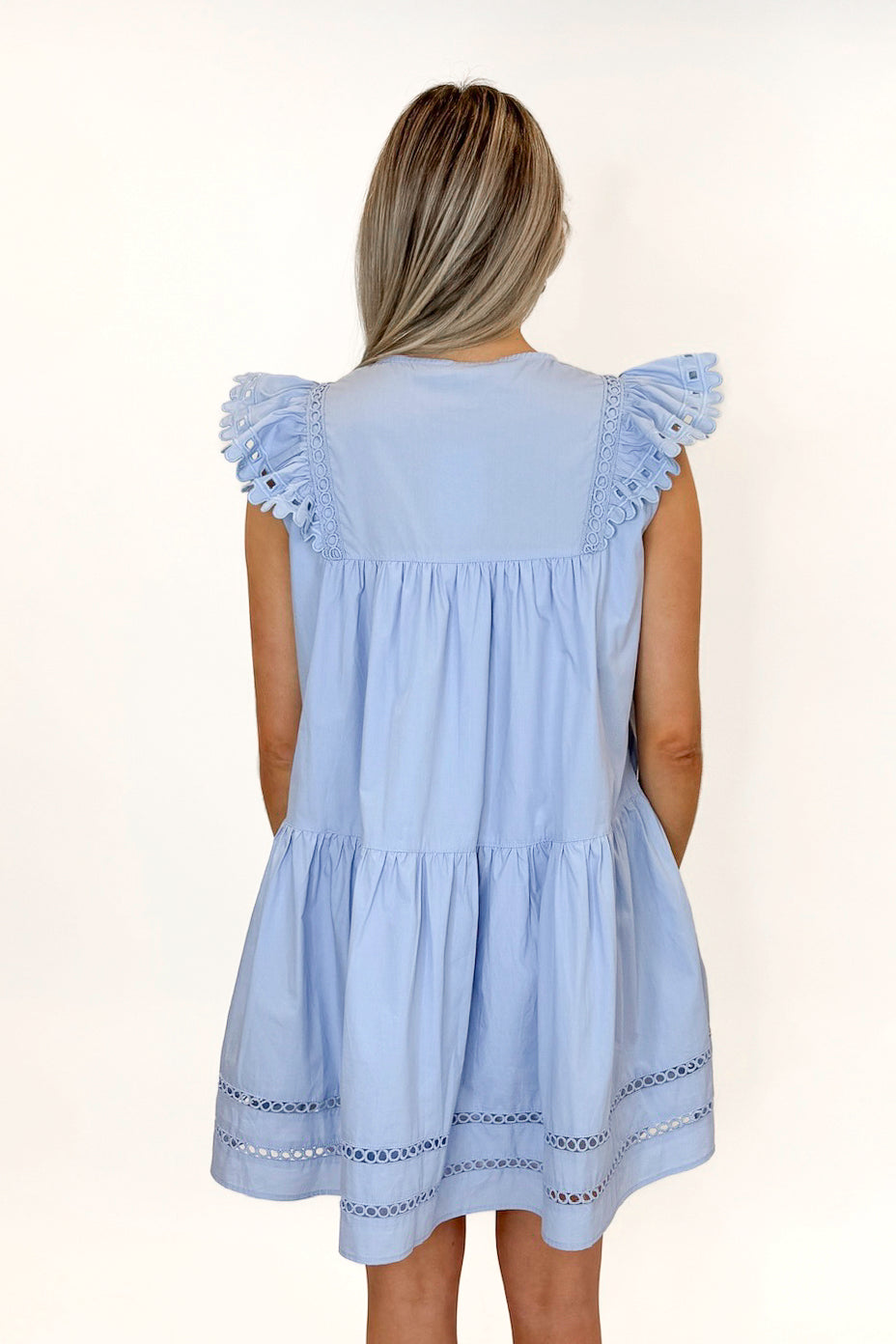 Back view of woman wearing Light Blue Eyelet Detail Dress with sandals against white studio background.