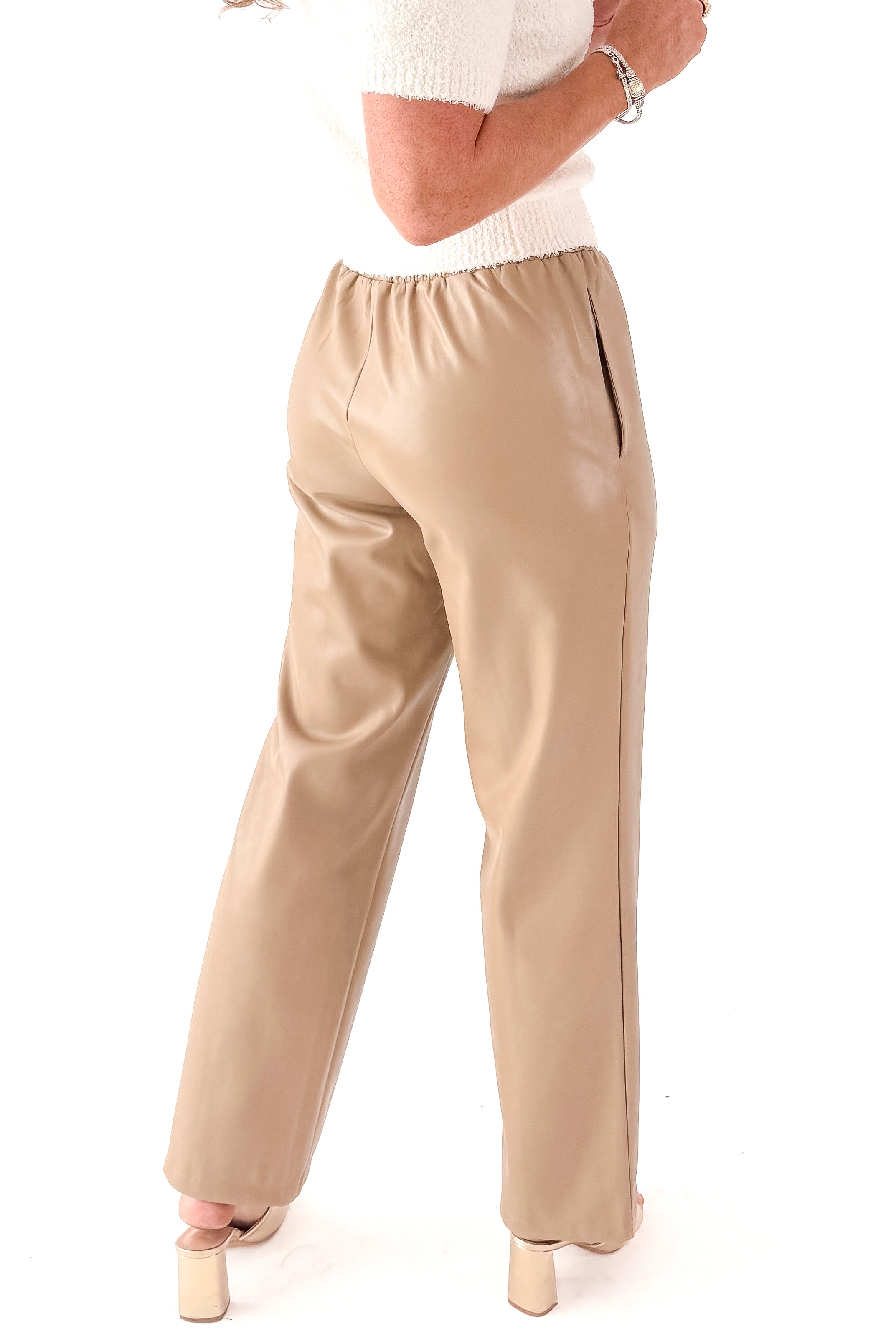 Side view of woman wearing Macchiato Faux Leather Pants and sweater against white studio background.