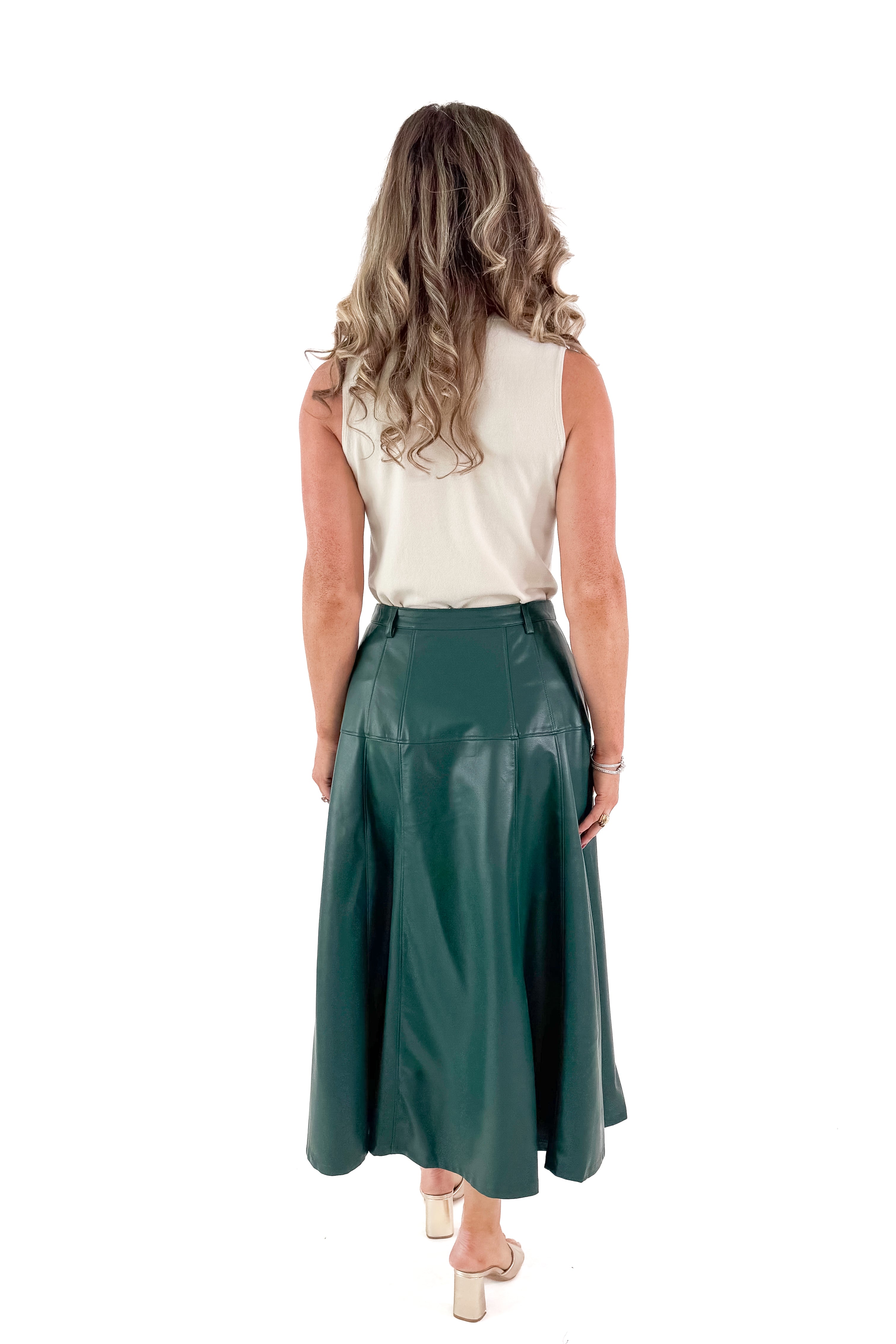 Back view of woman wearing Hunter Green Faux Leather Midi Skirt with top against white studio background.