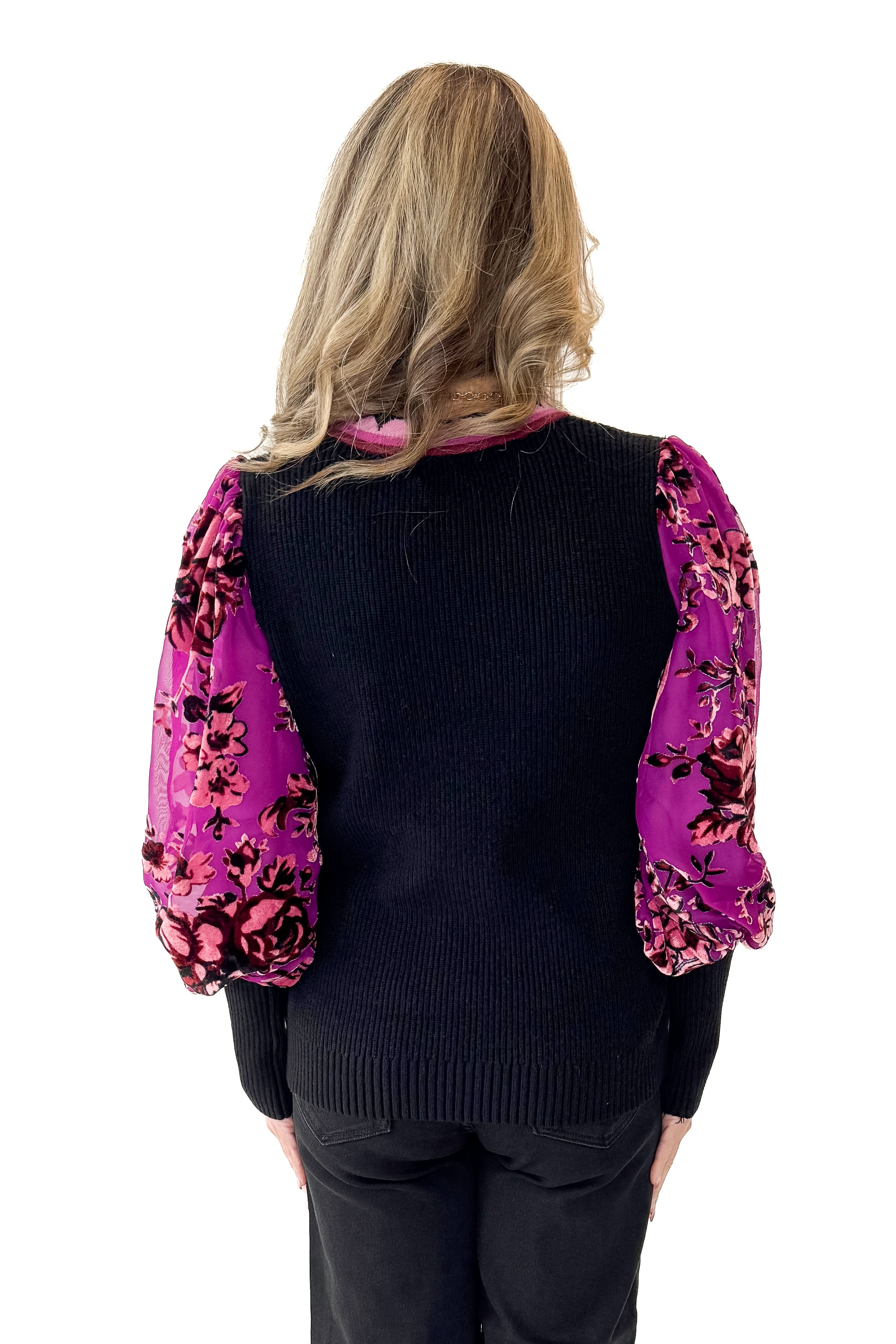 Woman wearing a black sweater with a colorful floral sleeves in front white background back view.