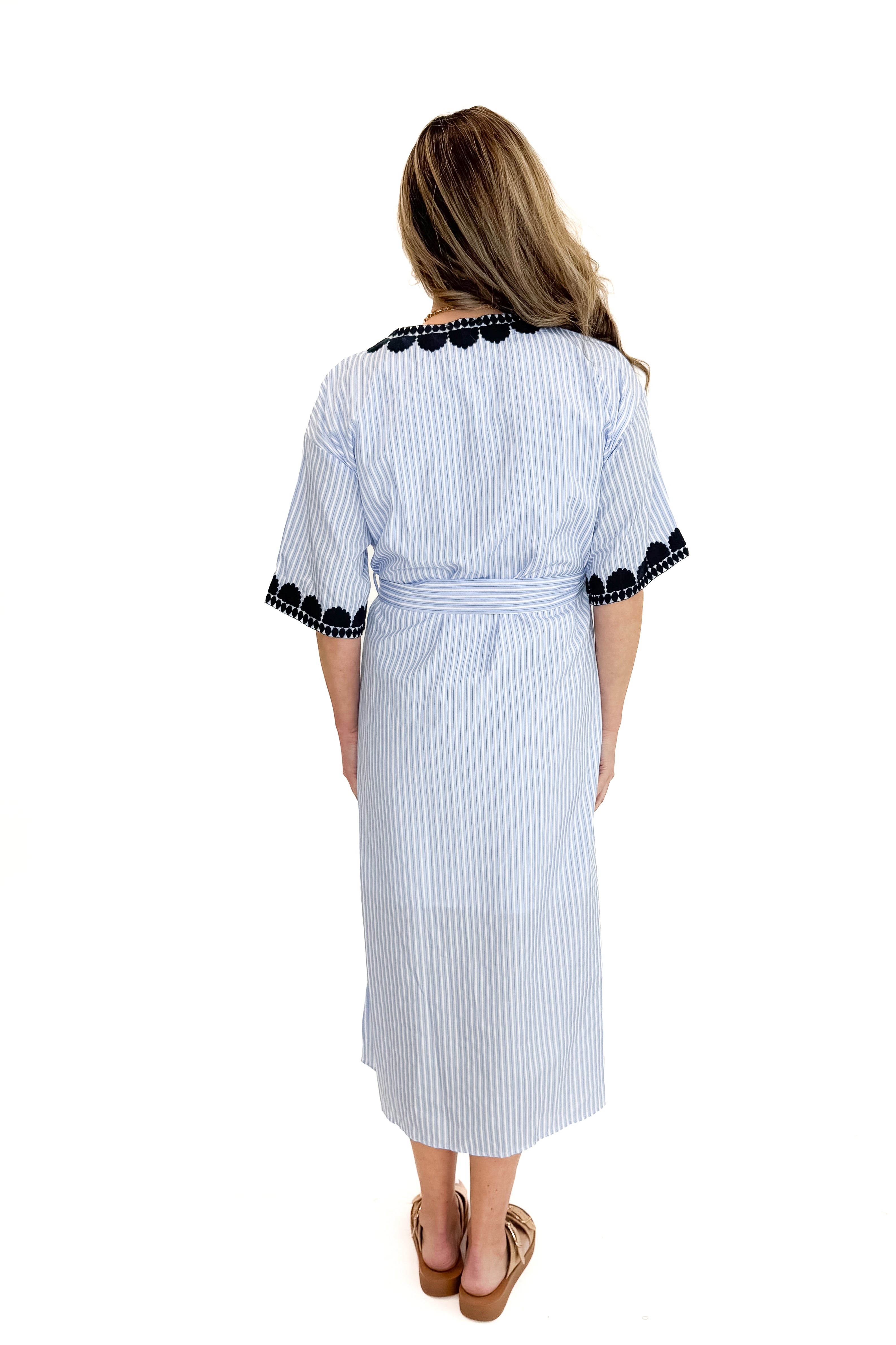 Back view of woman wearing Blue Striped Embroidery Accent Midi Dress with sandals against white studio background.