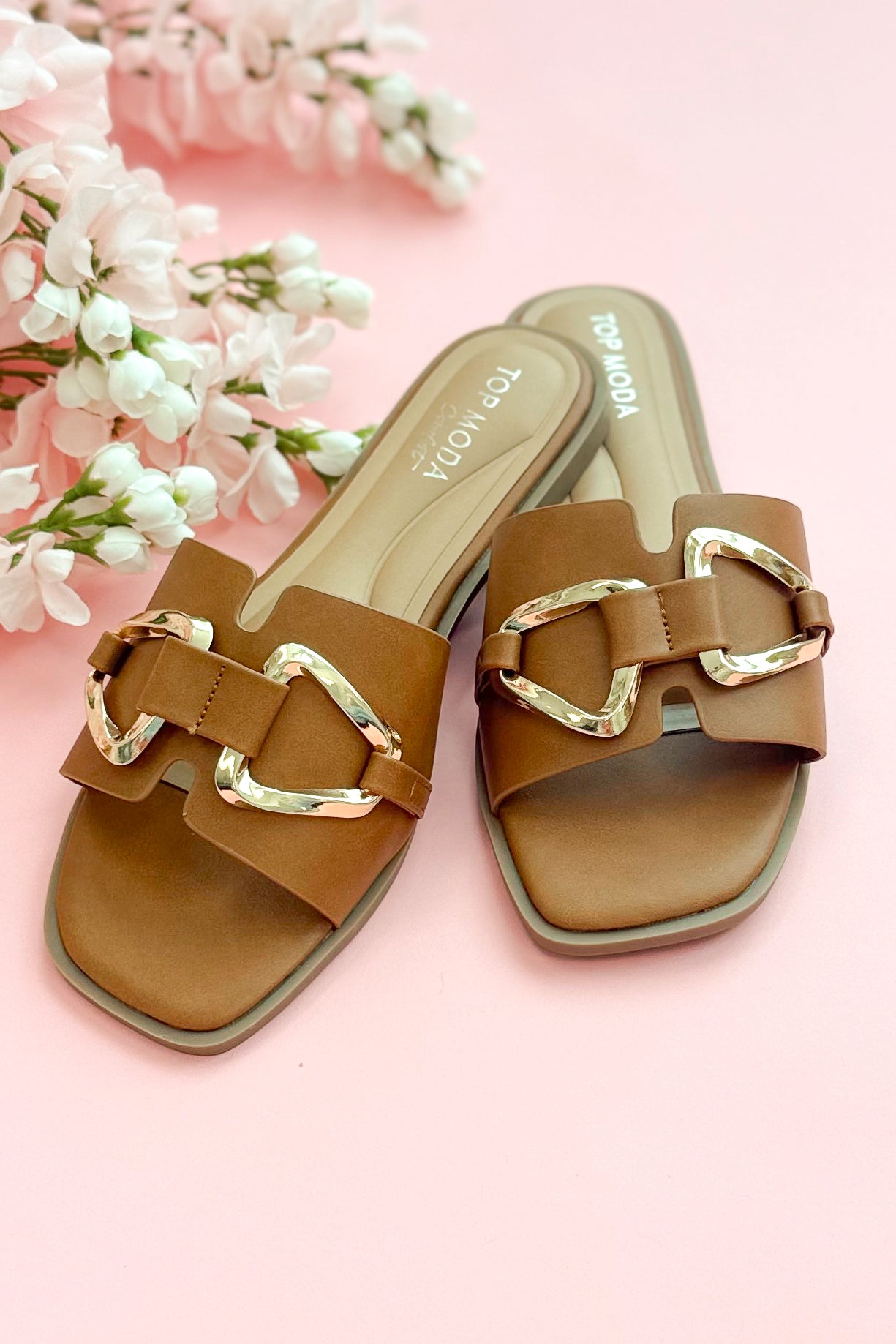 Front view of Gelato- Tan Buckle Detail Sandals against pink studio background.