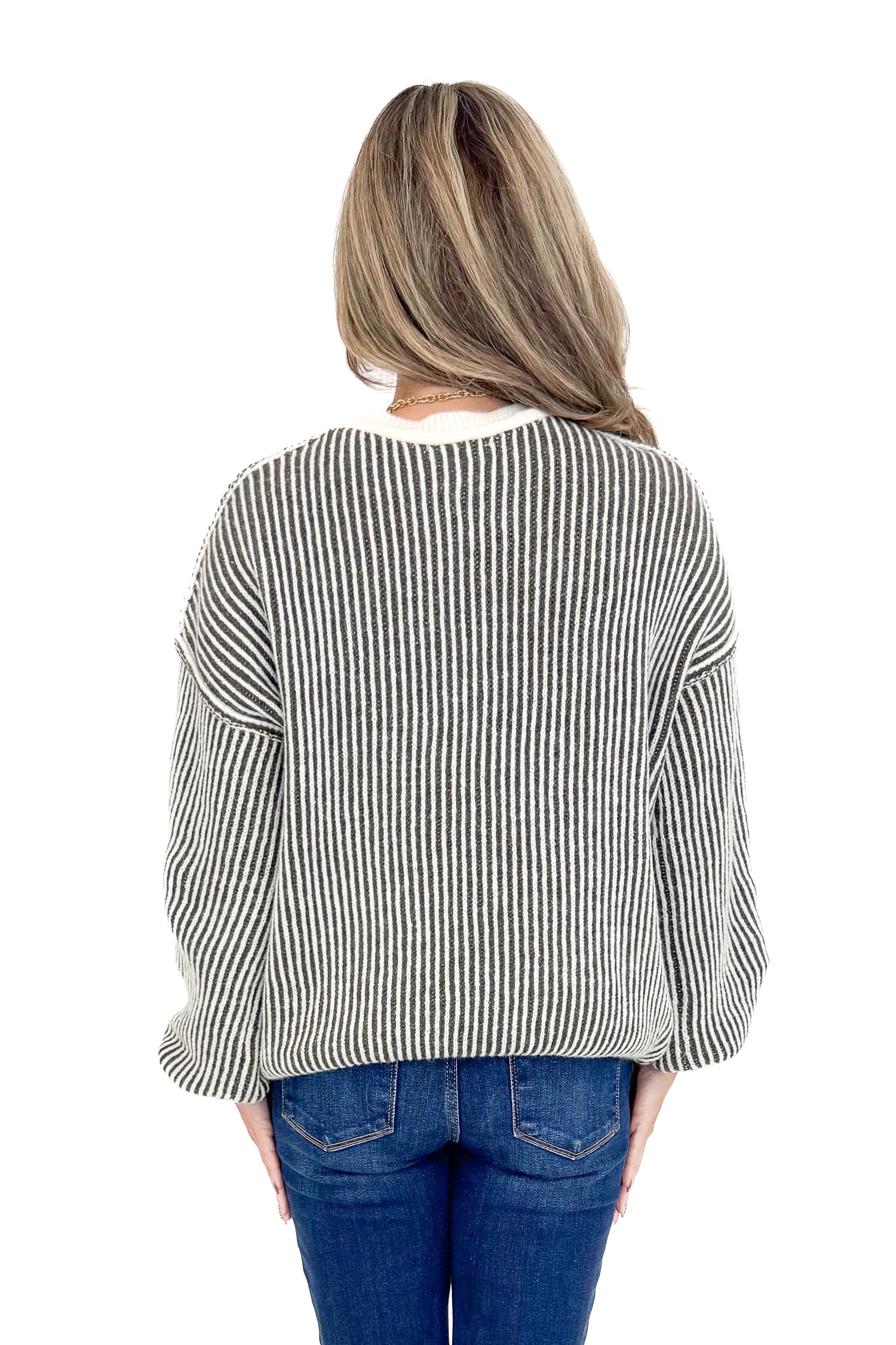 Back view of woman wearing Cream and Charcoal Striped Sweater with jeans against white studio background.