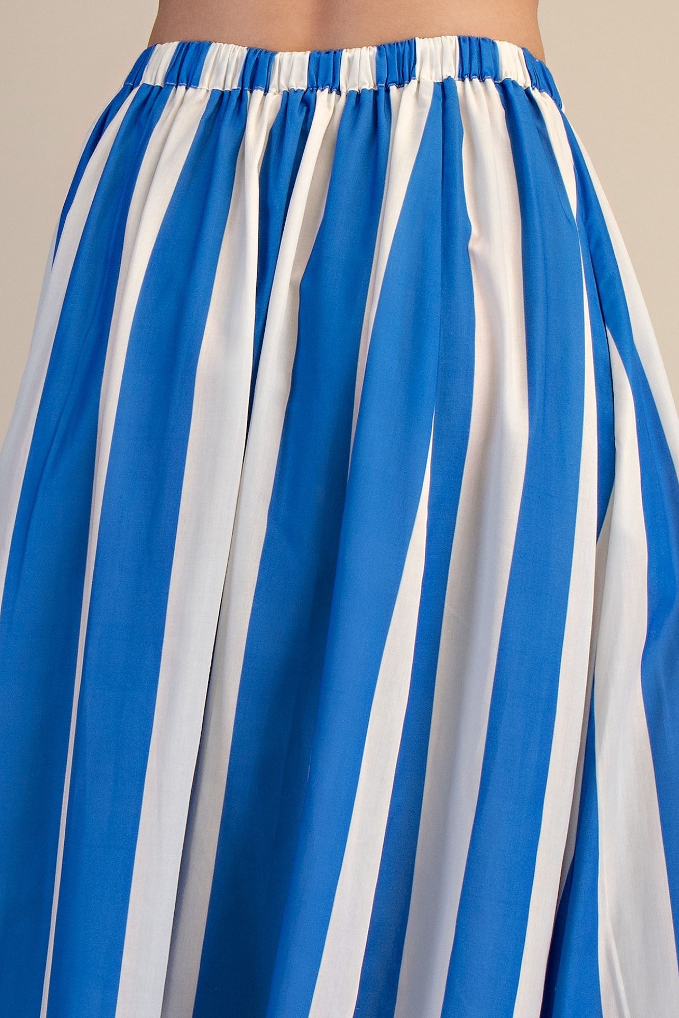Back detail view of woman wearing Blue & White Striped Skirt against studio background.