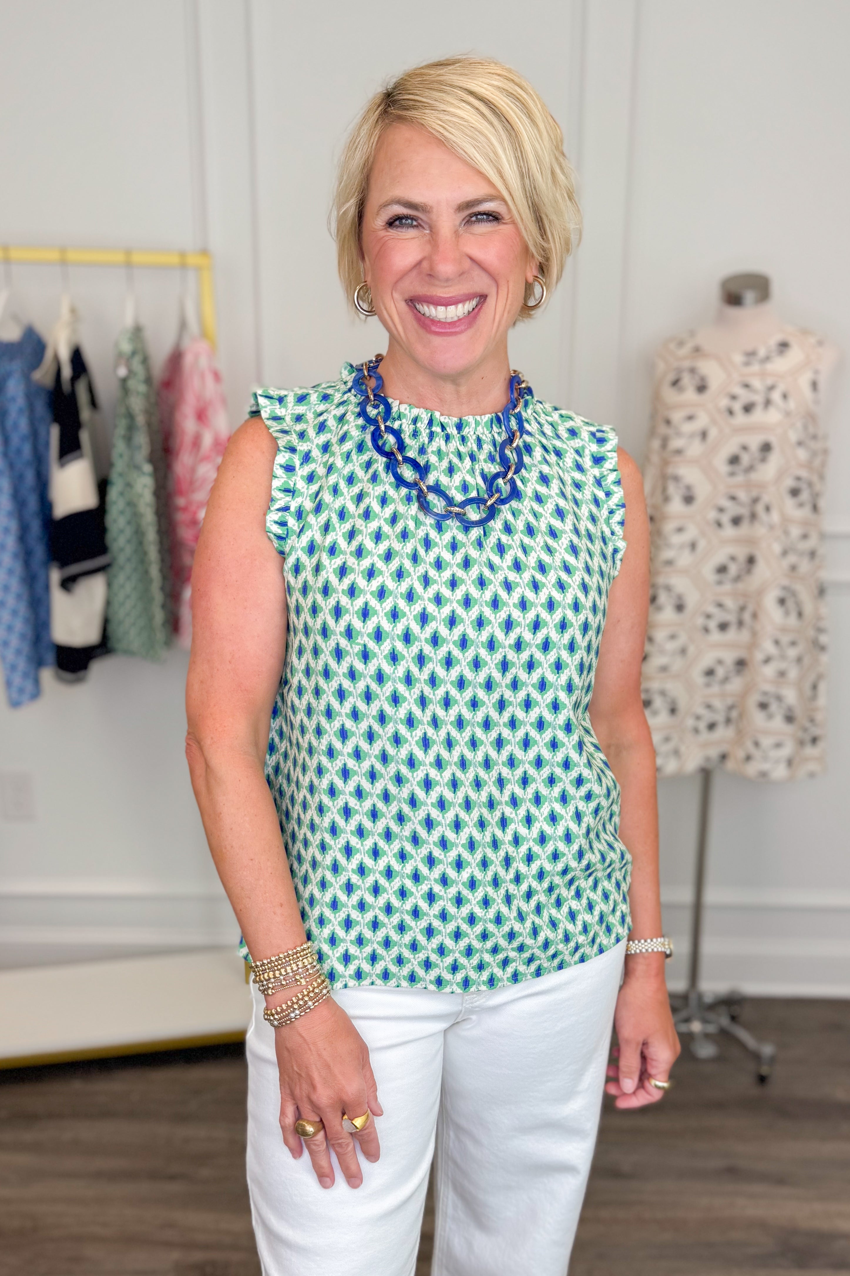 Woman wearing Green & Blue Abstract Printed Tank and white pants in a clothing store setting