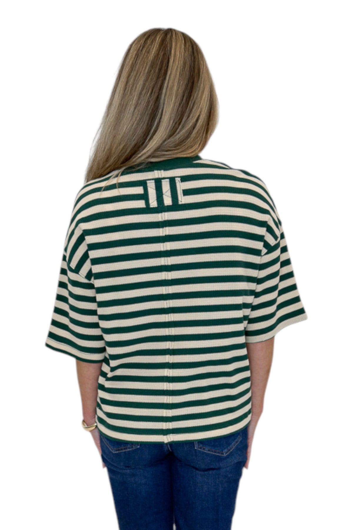 Back view of woman wearing Swagger Boutique’s Green & Cream Striped Textured Tee by Entro with jeans against white studio background.