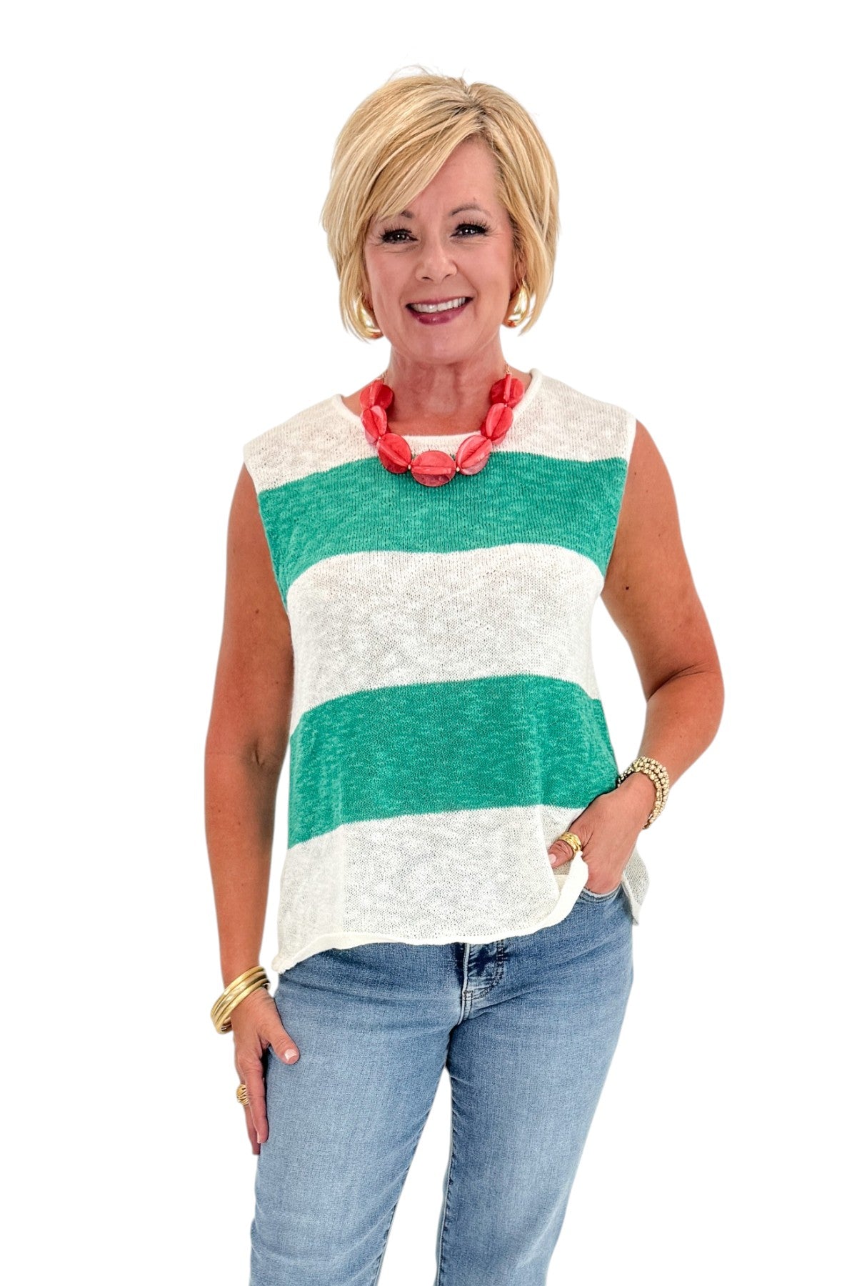 Front view of woman wearing Swagger Boutiqueās Green & White Striped Sleeveless Sweater with jeans against white studio background.