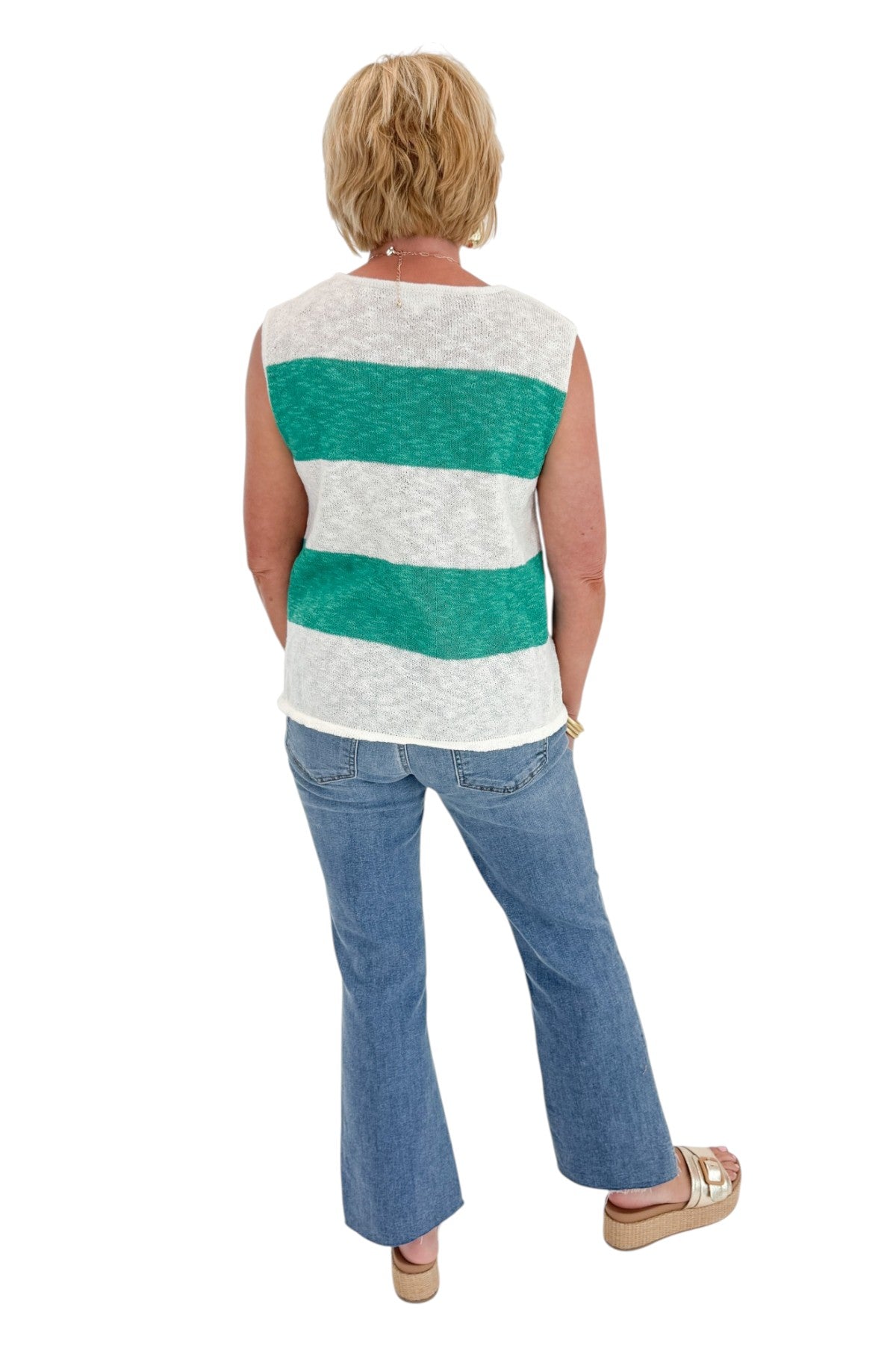 Back view of woman wearing Swagger Boutiqueās Green & White Striped Sleeveless Sweater with jeans against white studio background.