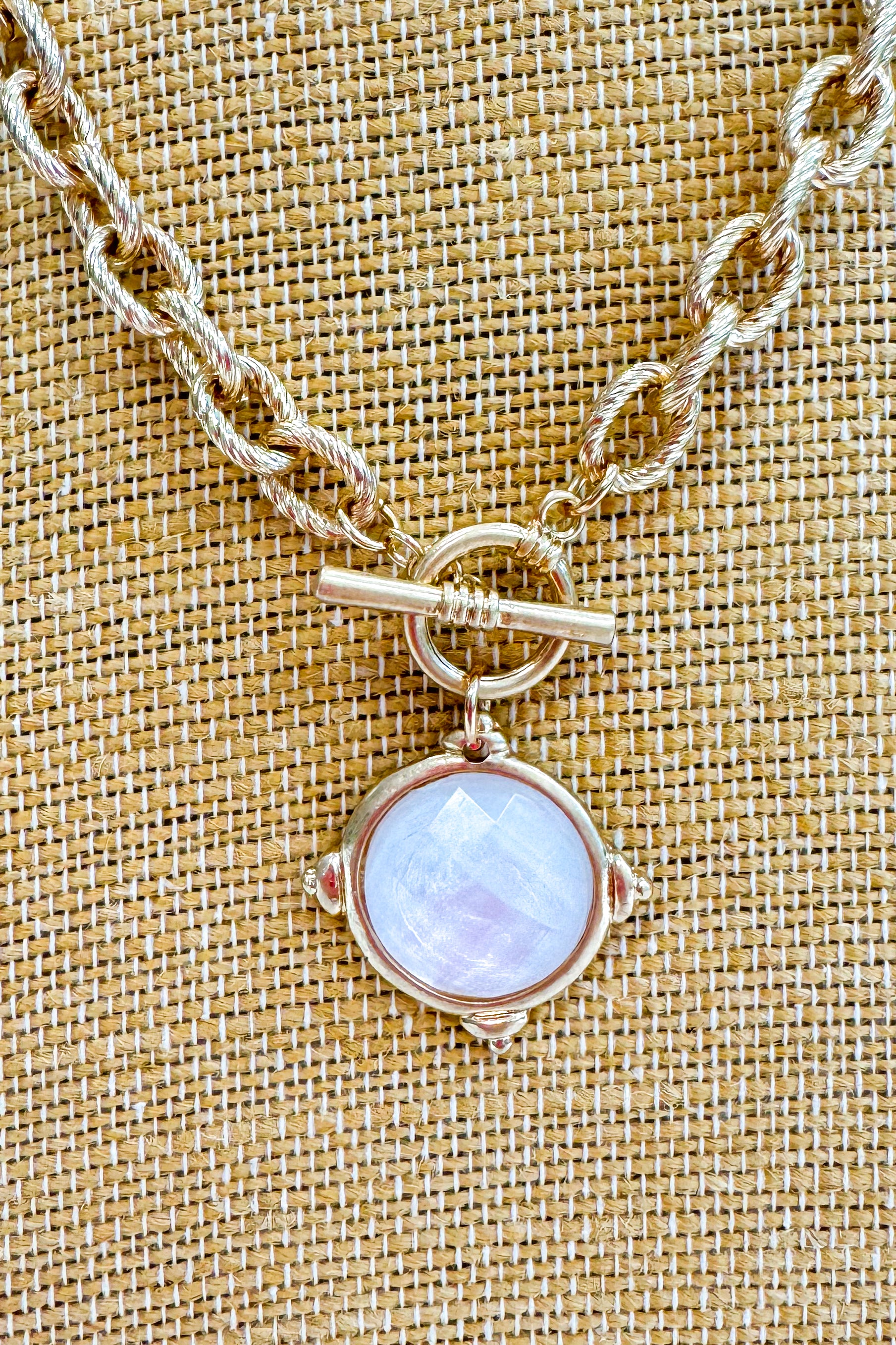 Necklace with a round pendant on a textured beige background