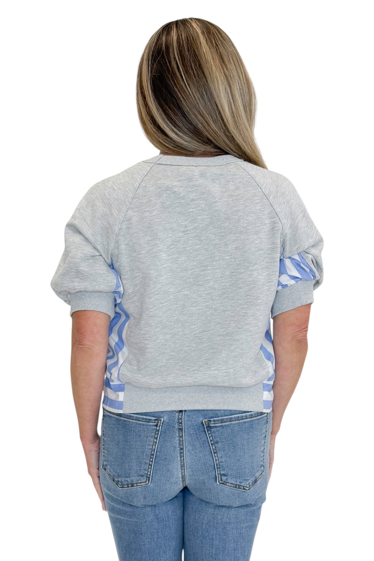 Back view of woman wearing Swagger Boutiqueās Grey Striped Short Sleeve Sweatshirt with jeans against white studio background.