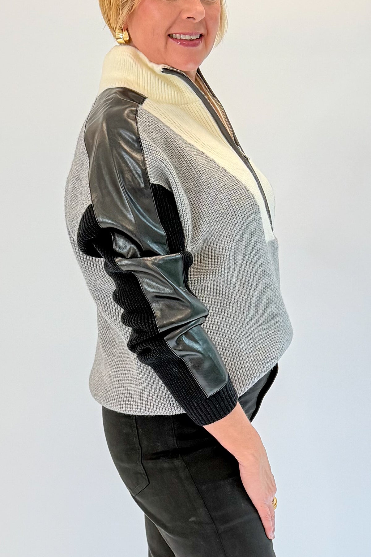 Side detail view of woman wearing Swagger Boutique’s Grey & Black Color Block 1/4 Zip Sweater with jeans against white studio background.
