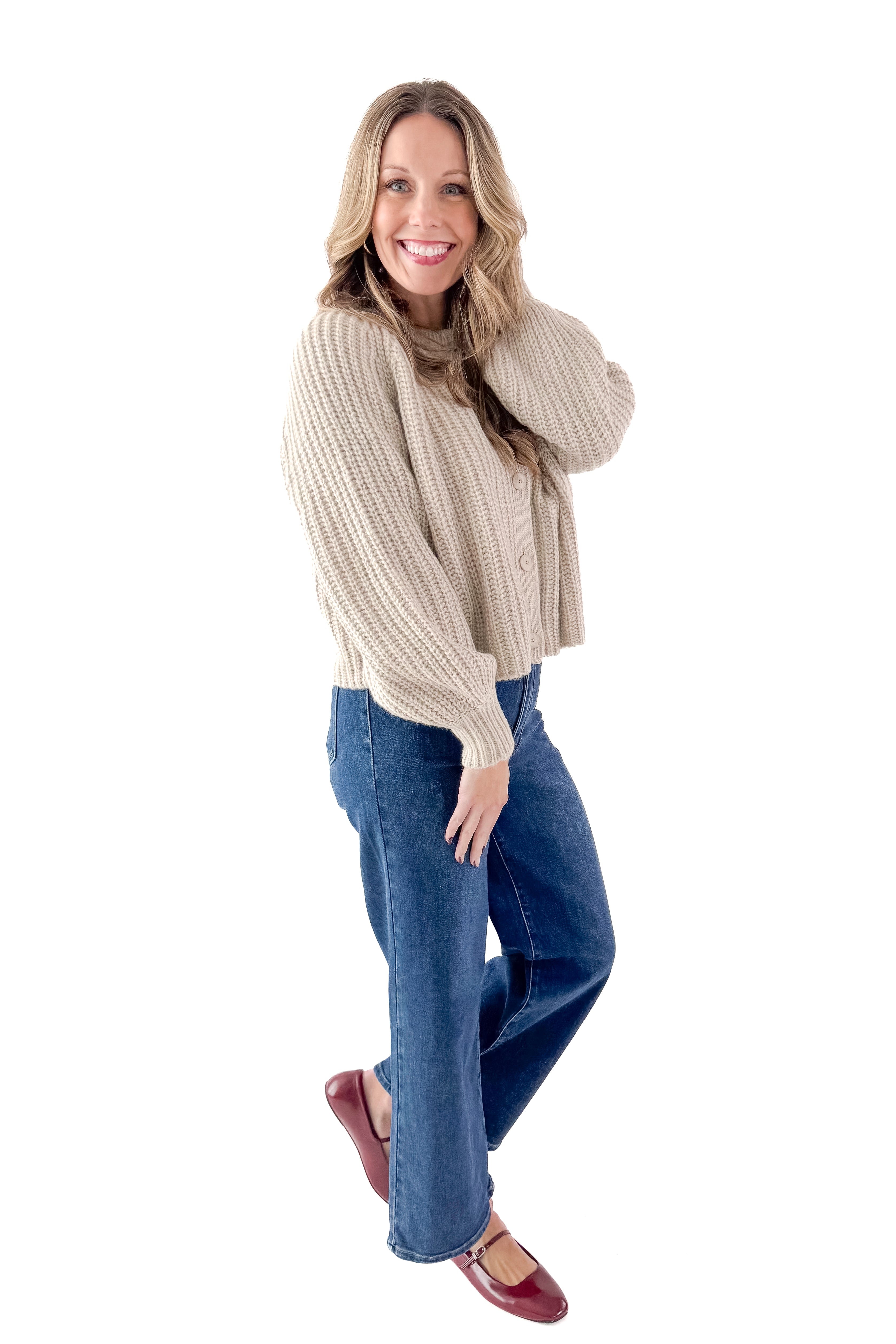 Side view of woman wearing Light Mocha Button Up Cardigan with jeans against white studio background.