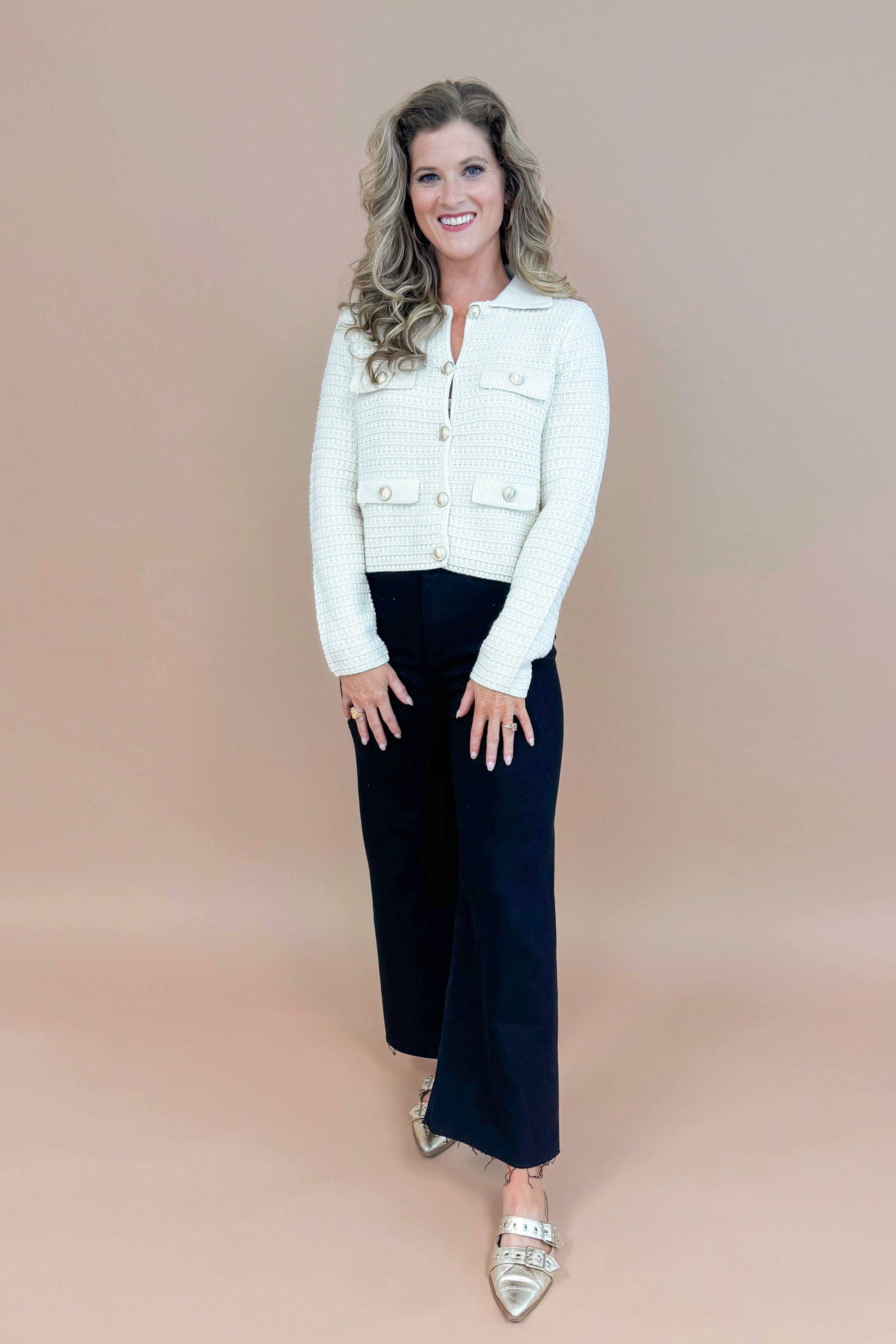 Picture of woman wearing Cream Textured Button Up Cardigan and jeans with taupe background.