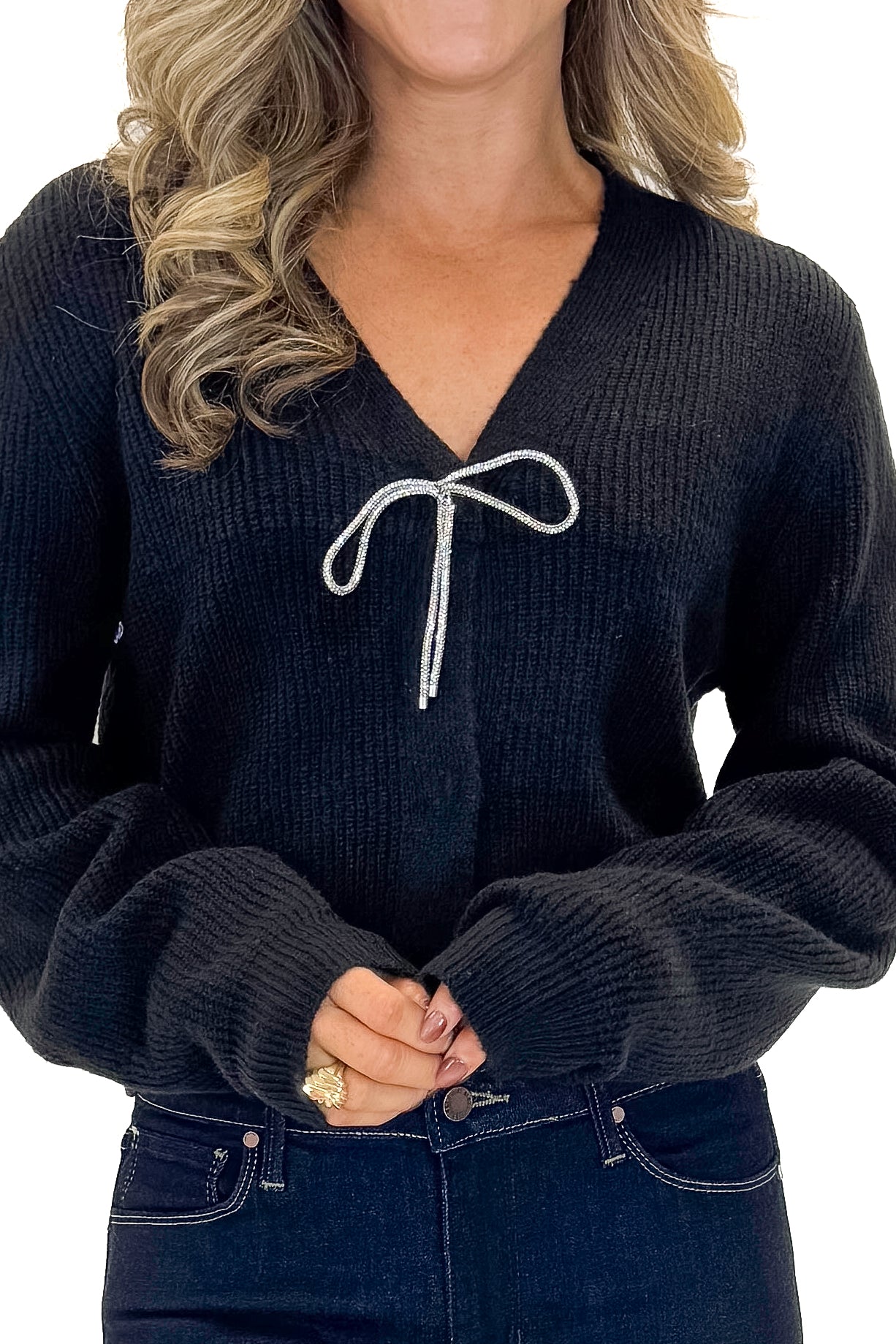Front detail view of woman wearing Black Cardigan With Rhinestone Bow with jeans against white studio background.