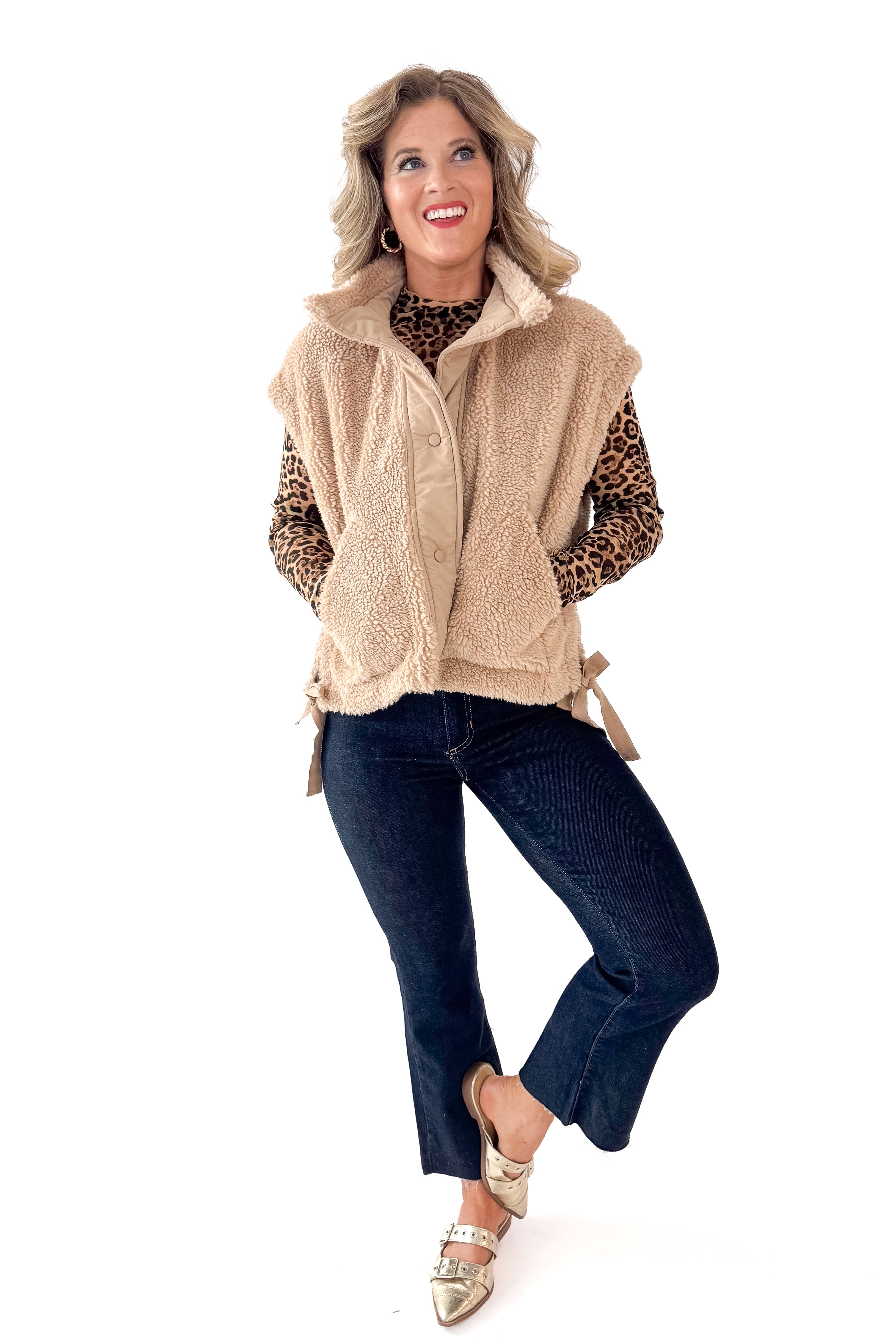 Front view of woman wearing Taupe Sherpa Button Up Vest with jeans against white studio background.