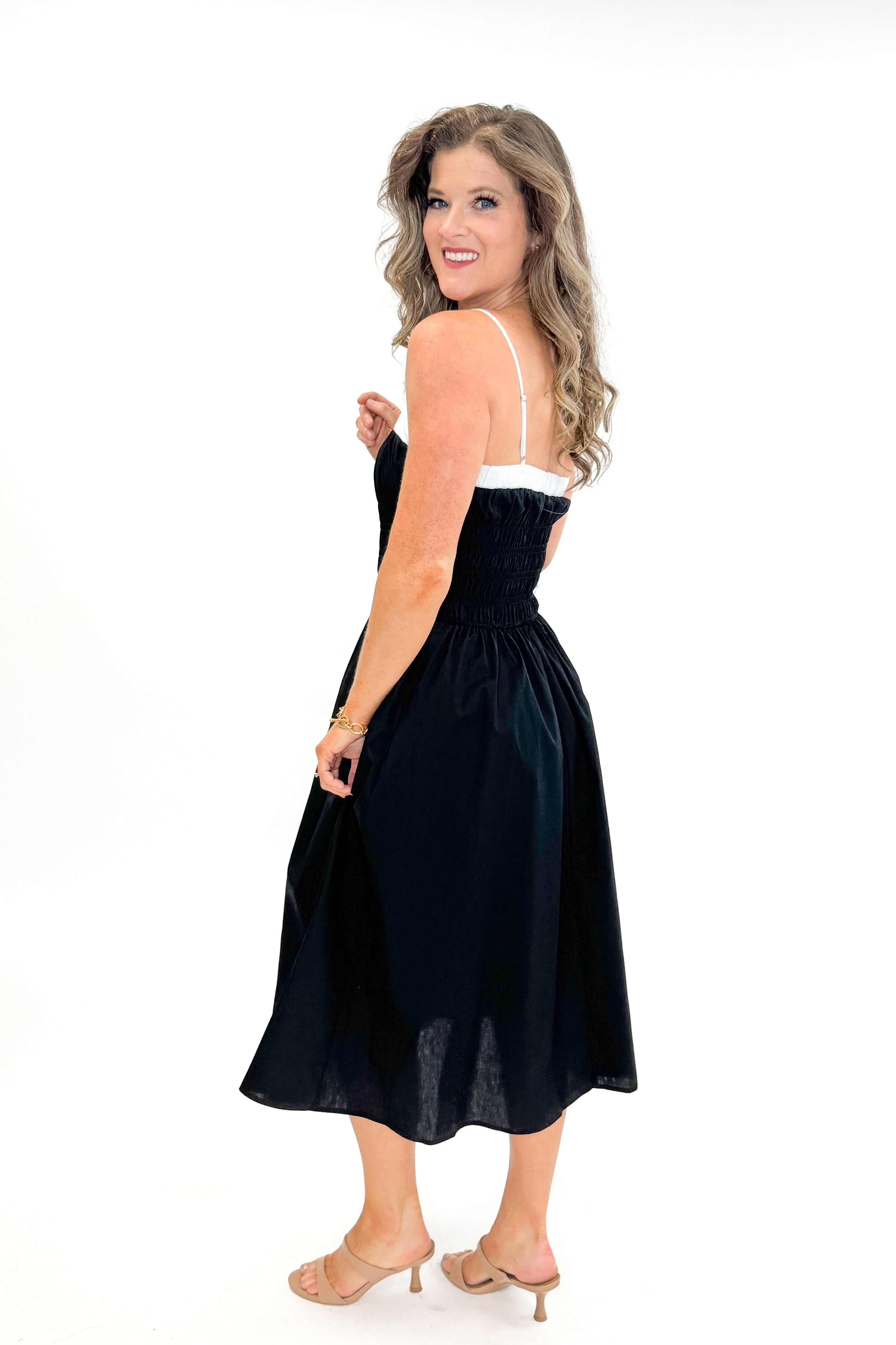 Side view of woman wearing Black With White Color Block Smocked Midi Dress against white studio background.