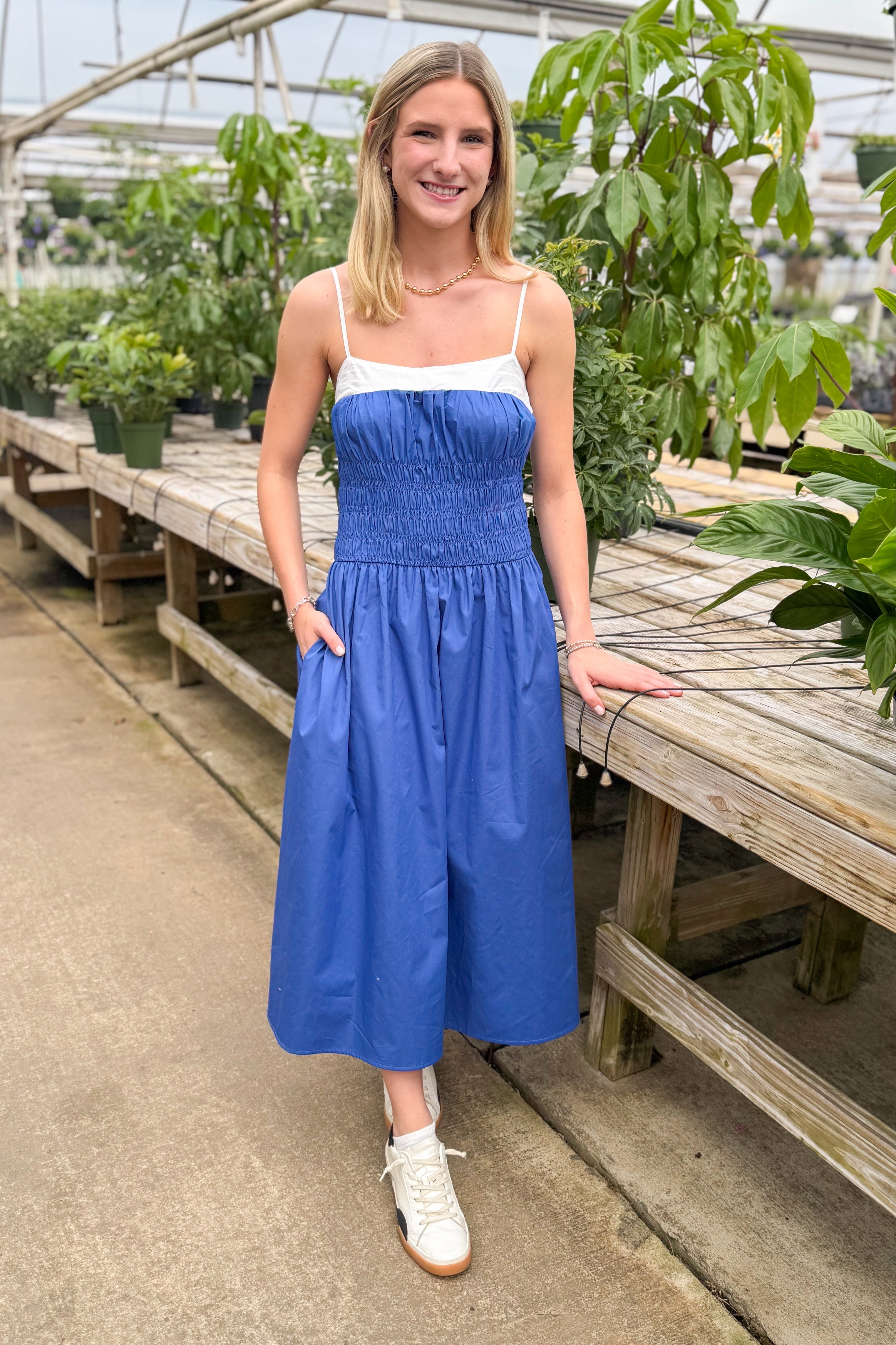 Front view of woman wearing Blue With White Color Block Smocked Midi Dress at a garden center.