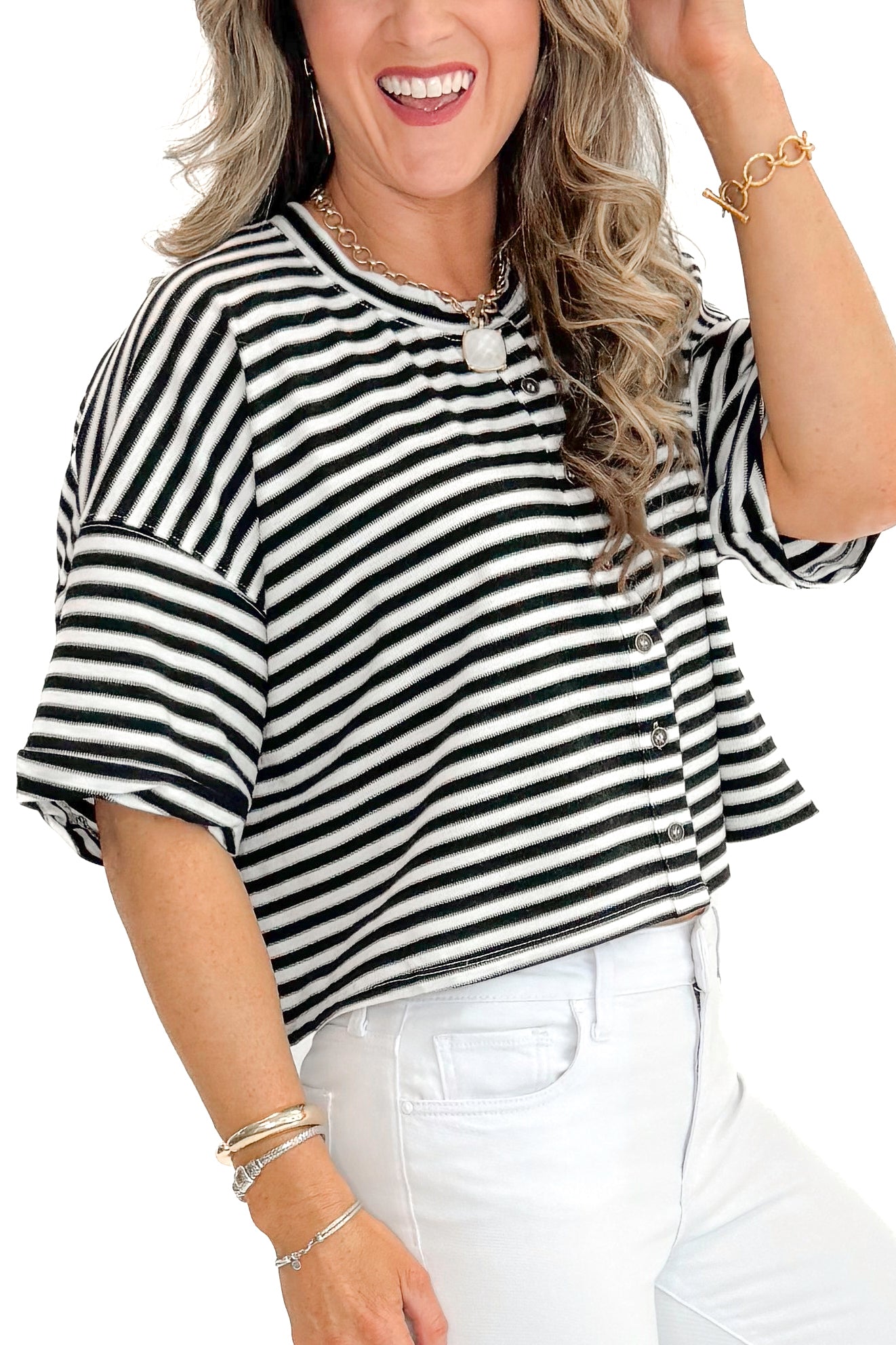 Side detail view of woman wearing Black & White Striped Button Up Tee with jeans against white studio background.