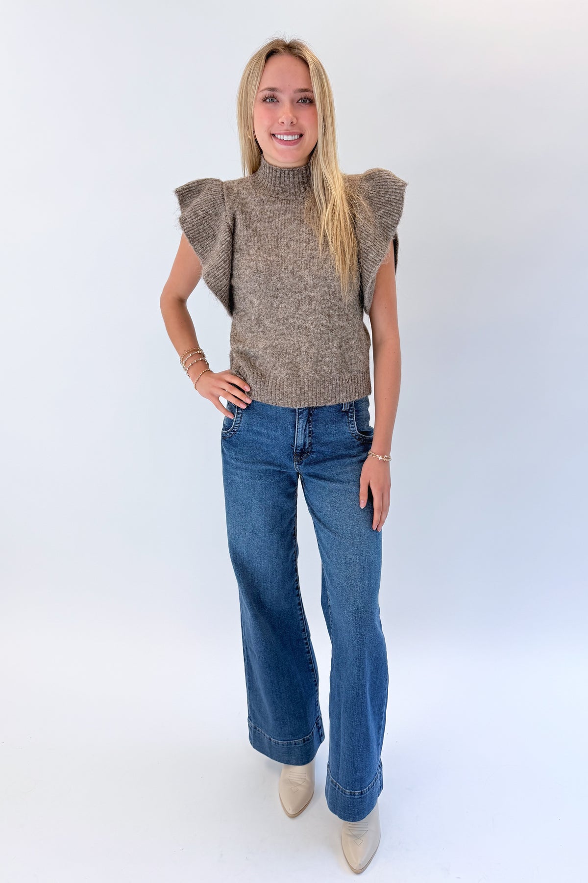 Front view of woman wearing Swagger Boutique’s Heathered Taupe Short Flutter Sleeve Sweater by Entro with jeans against white studio background.